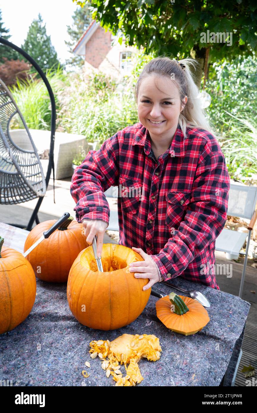 Femme blonde creusant et enlevant les graines des citrouilles comme décoration pour la saison d'Halloween Banque D'Images