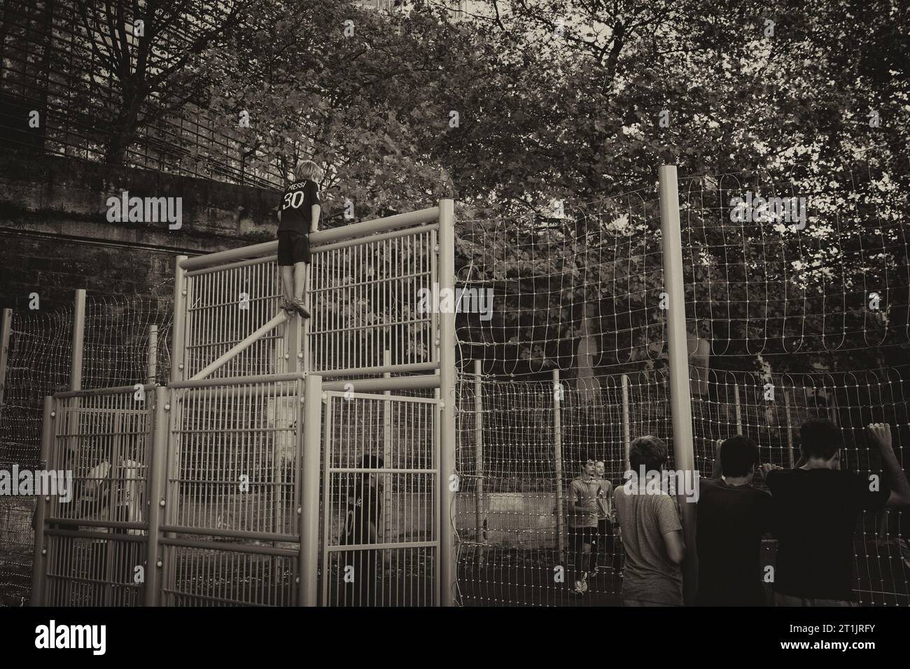 Futur joueur regardant les grands garçons jouer au futbol. Banque D'Images