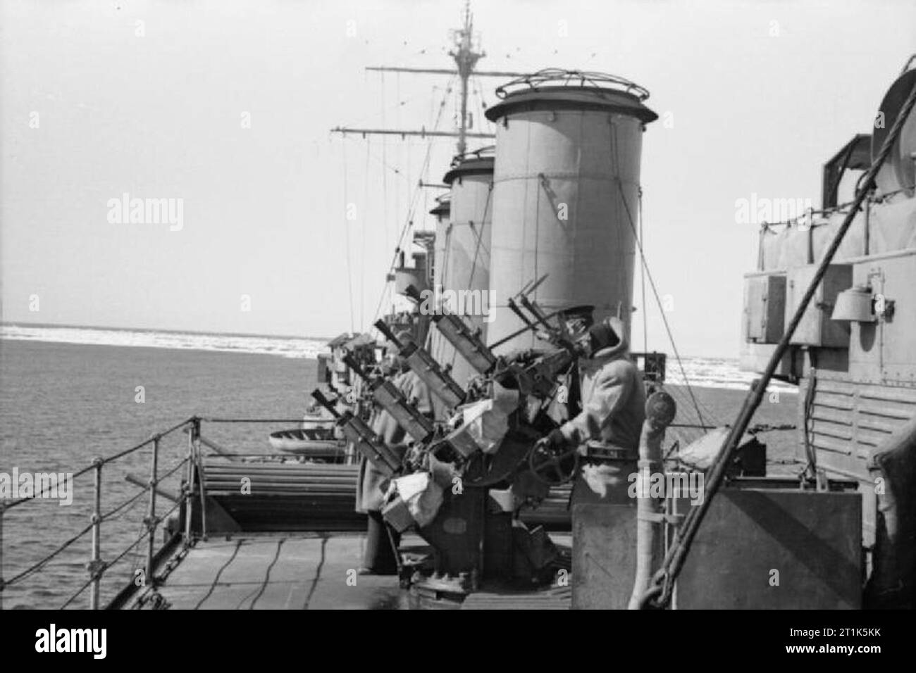 Le HMS Suffolk en patrouille dans le détroit de Danemark, 1941 à bord du HMS SUFFOLK sur une patrouille du Danemark Straights, entre l'Islande et le Groenland, 1941. L'écoulement des glaces peut être vu dans l'arrière-plan. Deux membres de l'équipage d'un homme de la quadruple 0.5' Vickers les mitrailleuses située au milieu du bateau, tandis qu'un troisième agit comme Lookout. Banque D'Images