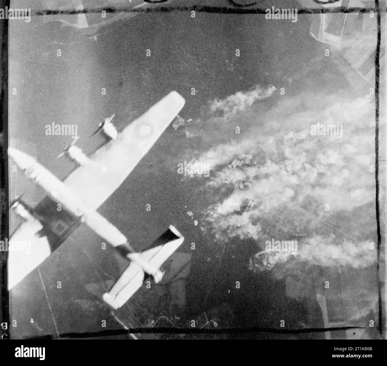 Royal Air Force Bomber Command, 1942-1945. La lumière du soleil du soir brille sur un Handley Page Halifax, lors d'une attaque sur un site de la bombe volante dans le Pas-de-Calais, France, comme la fumée d'indicateurs cibles s'élève de la cible. Banque D'Images