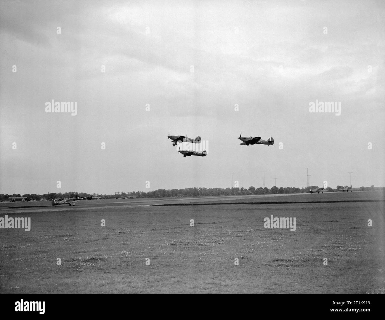 Le Fighter Command de la Royal Air Force, 1939-1945. Un vol de Hawker Hurricane marque est d'No 151 Squadron RAF décoller de North Weald, Essex, tandis qu'au-dessous d'eux, les ouragans de 56 Squadron RAF taxi jusqu'à l'extrémité nord de la piste principale. Derrière eux, on peut voir le mâts sans fil de la station radio de l'objet Stratégie de Weald Gullet. Banque D'Images