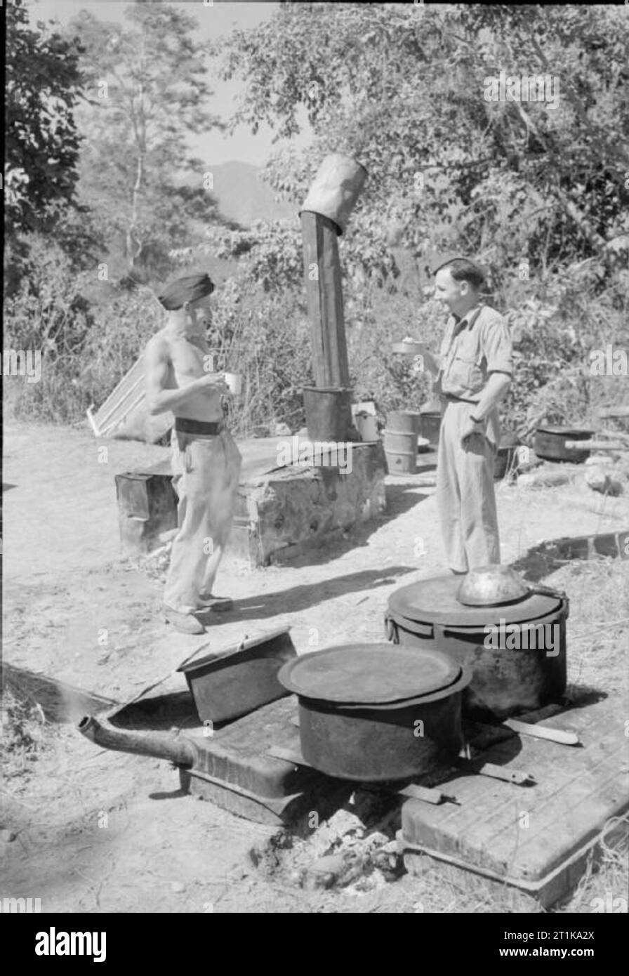Opérations de la Royal Air Force dans l'Extrême-Orient, 1941-1945. Deux cuisiniers à une unité de réparation en transport de la RAF en Birmanie centrale, prendre une pause du matin devant leurs deux poêles, fabriqué à partir de bidons d'essence et de munitions récupérées des boîtes. Ils sont, (à gauche) Le caporal W J Trennery de Penzance, Cornwall, et le caporal G W Fontaine de Leighton Buzzard, Bedfordshire. Banque D'Images