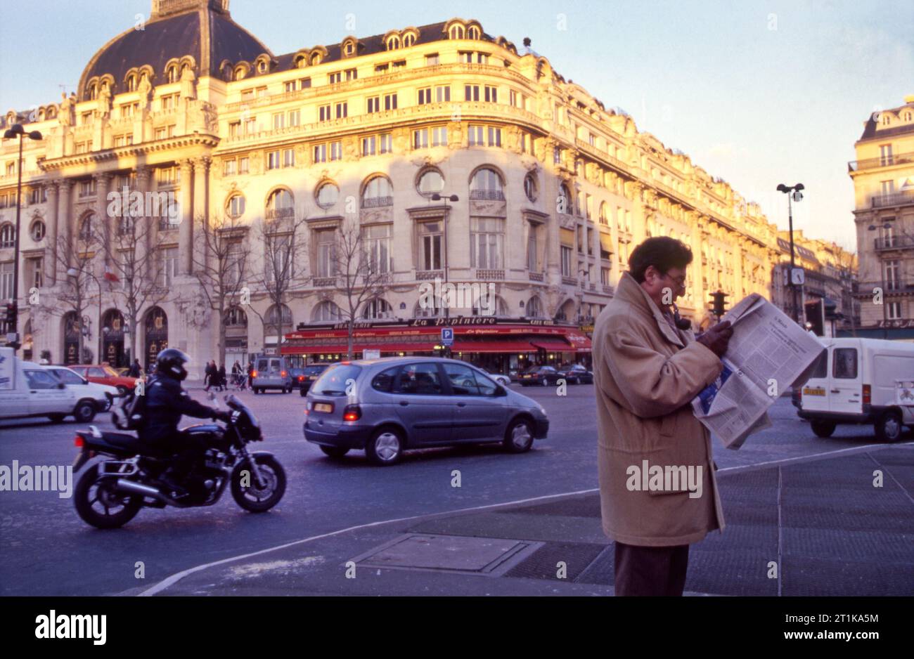 Homme à la pipe lit le journal le monde au coin d'une rue à Paris, France Banque D'Images