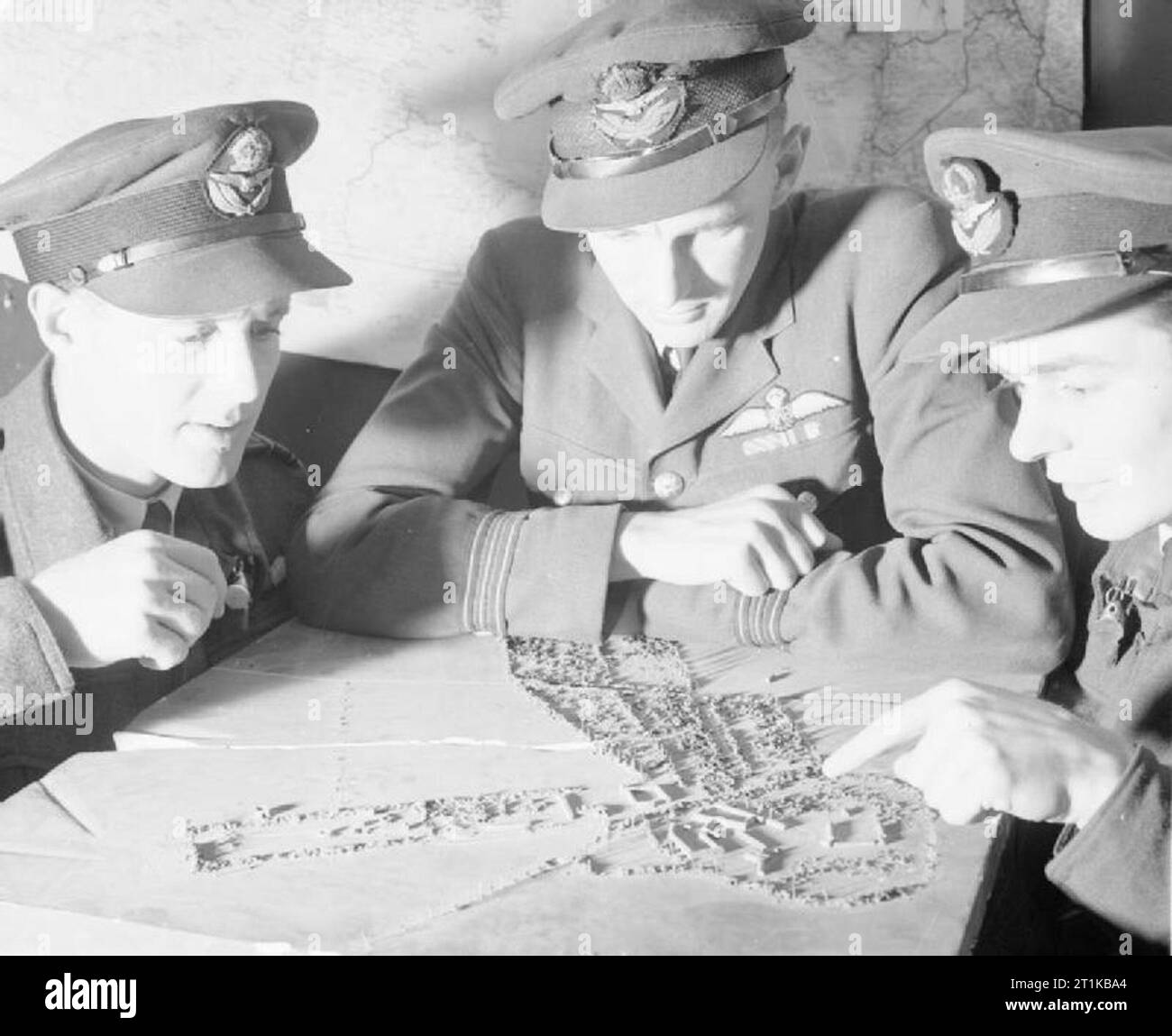 Royal Air Force- 2nd Tactical Air Force, 1943-1945. Le chef d'escadron K désireux (centre), un commandant de l'escadrille de l'Escadron n° 98 RAF, traite d'un modèle d'un site de lancement de fusées avec deux nouveaux venus à l'unité à Dunsfold, Surrey ; le chef d'Escadron R en bois (à gauche) et un pilote canadien, le Freeman (à droite). Banque D'Images