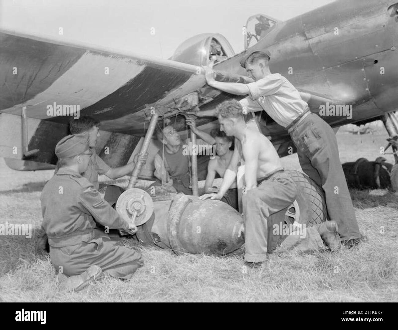 Royal Air Force- 2nd Tactical Air Force, 1943-1945. Les armuriers de No 122 Squadron RAF hisser un 1 000 lb-bomb en position sur une Mustang de l'Amérique du Nord Mark III, avec l'aide d'une bombe à main, treuil à B12/d'Ellon, Normandie. De gauche à droite : Le Caporal W H Glover, de Leicester, l'Aviateur-chef Hammond de Bromley, l'Aviateur-chef Baril de York, l'Aviateur-chef J Taylor de Huddersfield et de l'Aviateur-chef S R Powell de Much Hadham, Herts. Banque D'Images