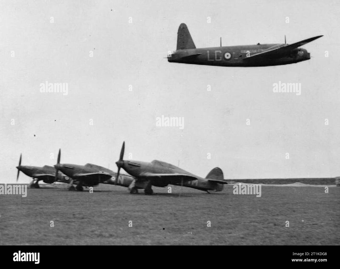 Royal Air Force Bomber Command, 1939-1941. Un Vickers Wellington Mark I, L4387 'LG-l', du No. 215 Squadron RAF, survolant les Hawker Hurricanes stationnés à Wick, Caithness, au retour d'une sortie de reconnaissance. Le L4387 a été détaché au Coastal Command en avril 1940 pour une reconnaissance de jour de Narvik, en Norvège. Commentaire : Notez les hélices bipales originales sur le Hurricane Mk is. Banque D'Images