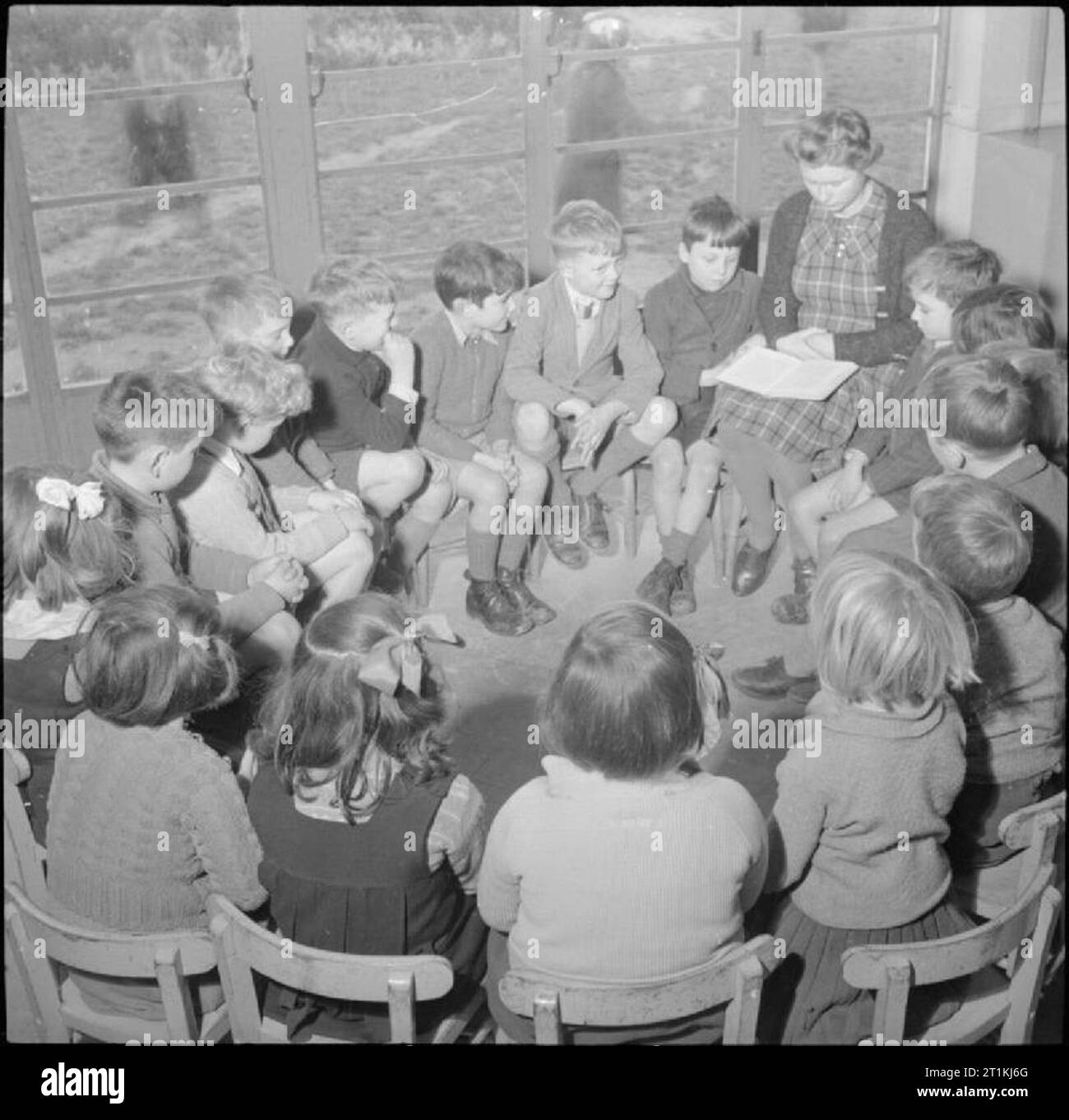 Une école du village moderne- l'éducation dans le Cambridgeshire, Angleterre, RU, 1944 Histoire du temps à Bottisham Junior School, Cambridgeshire. Les enfants sont assis en cercle et écouter que leur enseignant lit à eux. Banque D'Images