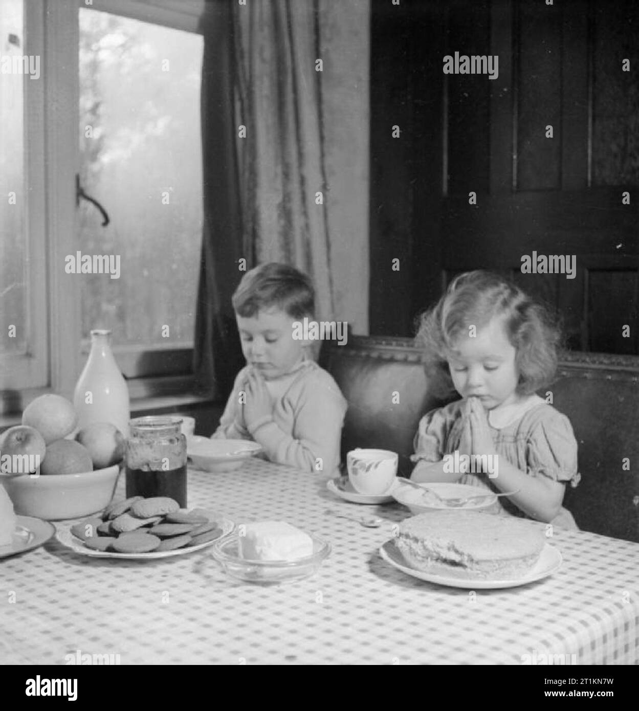 Les luxembourgeois en Angleterre- les sinistrés à Surrey, 1942 à l'âge de cinq ans, Andrew et sa sœur âgée de trois ans, Jacqueline dire Grace avant un repas à la maison dans laquelle ils séjournent à Surrey. Selon la légende originale, lorsqu'ils s'assoient pour manger qu'ils "n'oubliez jamais leurs grands-parents encore en Luxembourg, la nourriture est rare au Luxembourg maintenant'. Banque D'Images