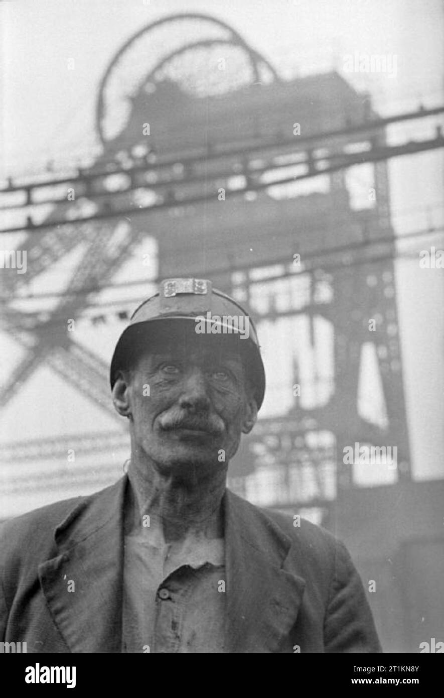 Homme de la Mine- La vie à la face du charbon, Grande-Bretagne, 1942, une substitution, head and shoulders portrait de mineur de charbon Fred Woolhouse. Dans l'arrière-plan peut être vu la tête de puits, machines s'élevant au-dessus de lui. Banque D'Images