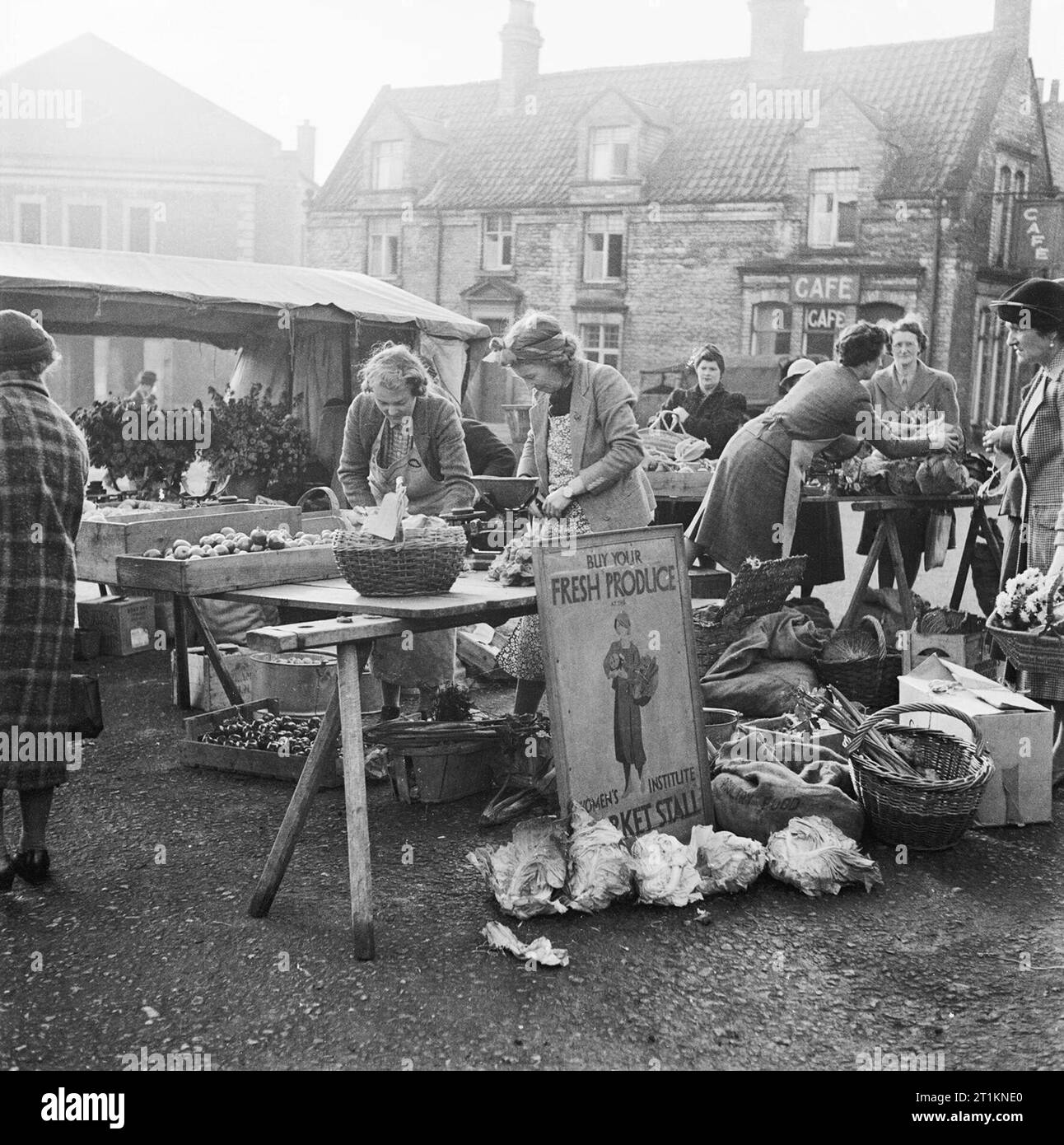 Membres de l'Institut des femmes (WI) qui vendent des produits à domicile sur des étals à Malton, dans le Yorkshire, pendant la Seconde Guerre mondiale. Les femmes dans les services volontaires : membres de l'Institut des femmes (WI) qui vendent des produits à domicile sur des étals à Malton, dans le Yorkshire, en Angleterre. La photo montre Lady Worsley (au milieu à gauche) servant une livre de pommes de terre. Banque D'Images