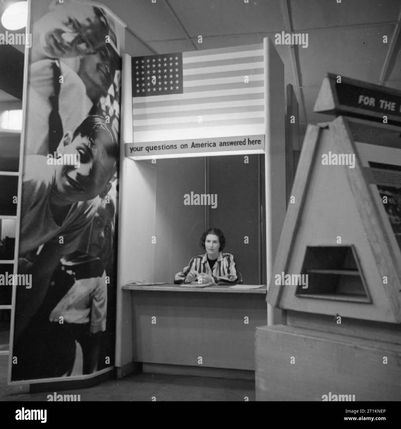 Ministère de l'information expositions pendant la Seconde Guerre mondiale, Londres, Angleterre, RU, 1943 UNE FEMME mans le kiosque d'information à une exposition intitulée "John Olsson - l'histoire d'un américain moyen, qui a eu lieu à la station de métro Charing Cross. L'exposition a été produite par le ministère de l'information, en collaboration avec le United States Office of War Information (OWI) et nous a raconté l'histoire de la maison américaine, par la vie de John Olsson. Banque D'Images