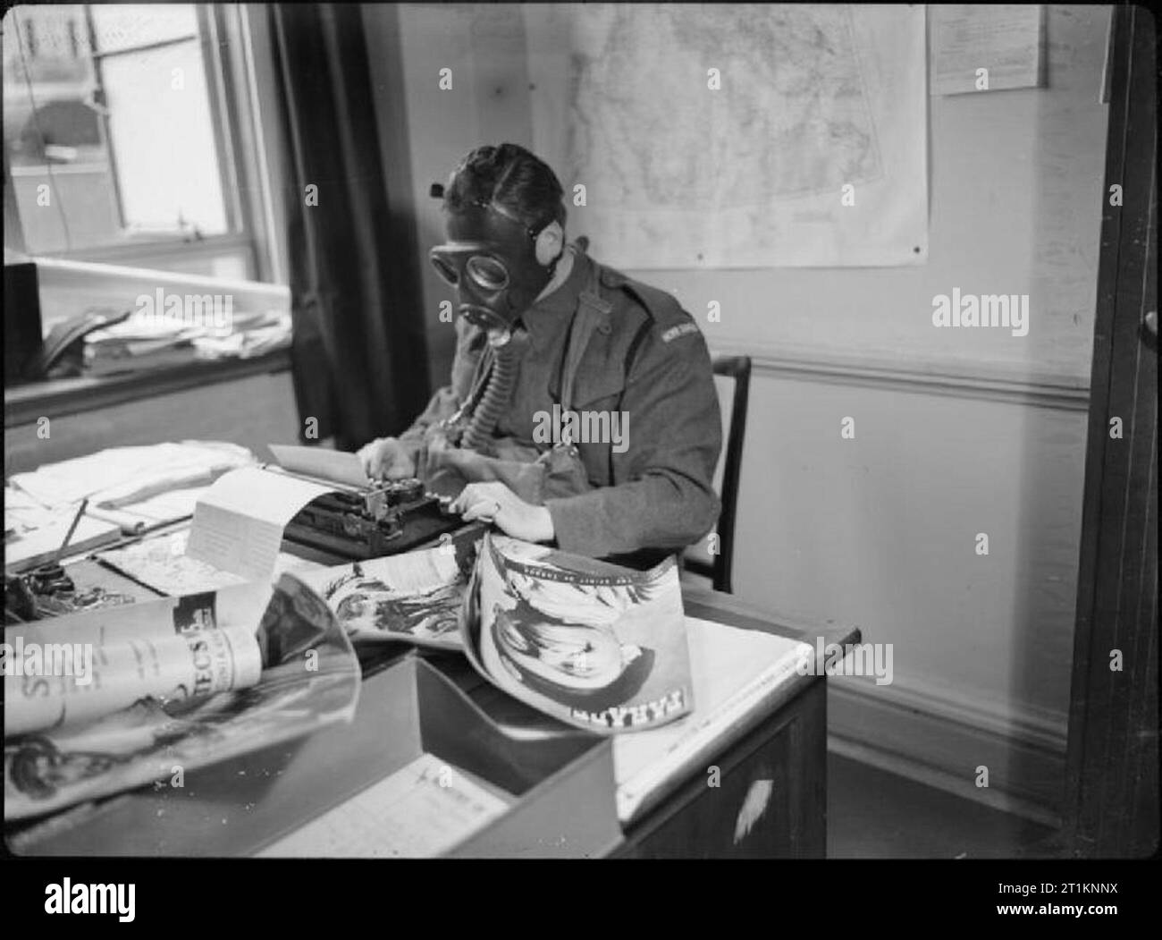 Précautions de protection de l'air en Grande-Bretagne - personnel du ministère de l'information porter des masques à gaz à travailler, Londres, Angleterre, 1941 L M La MacBride de la Division des publications du ministère de l'information envoie un câble à 'Parade' magazine. Il est caporal dans la Garde nationale et est vêtu de son uniforme et le devoir d'un masque à gaz comme il travaille. Banque D'Images