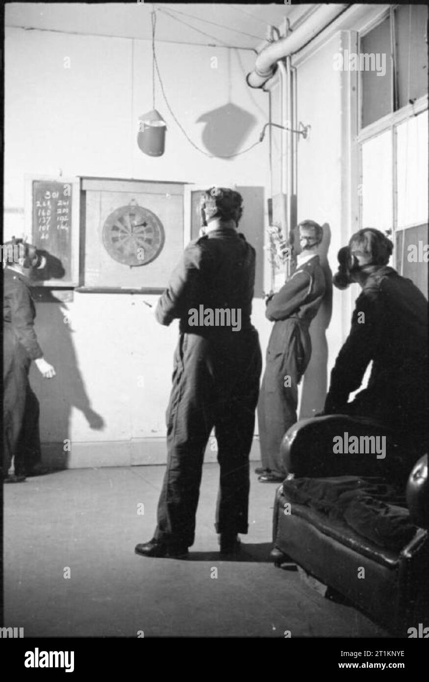 Précautions de protection de l'air sur le front intérieur britannique, C 1941 un groupe d'Air Raid Wardens vous détendre avec une partie de fléchettes à leur poste, ARP entre les appels. Tous portent leur devoir de masques à gaz, montrant que la vie peut continuer comme normale, même en portant un masque à gaz ! Banque D'Images
