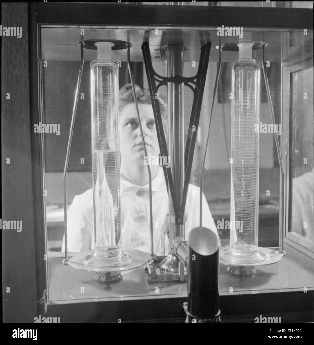 National Physical Laboratory- La science et la technologie en temps de guerre, Teddington, Middlesex, Angleterre, RU, 1944 à la Division Métrologie du National Physical Laboratory, un scientifique féminin. verrerie volumétrique tests 'Le cylindre gradué sur la gauche est à l'essai en pesant le contenu de l'eau sur un équilibre très sensible". Banque D'Images