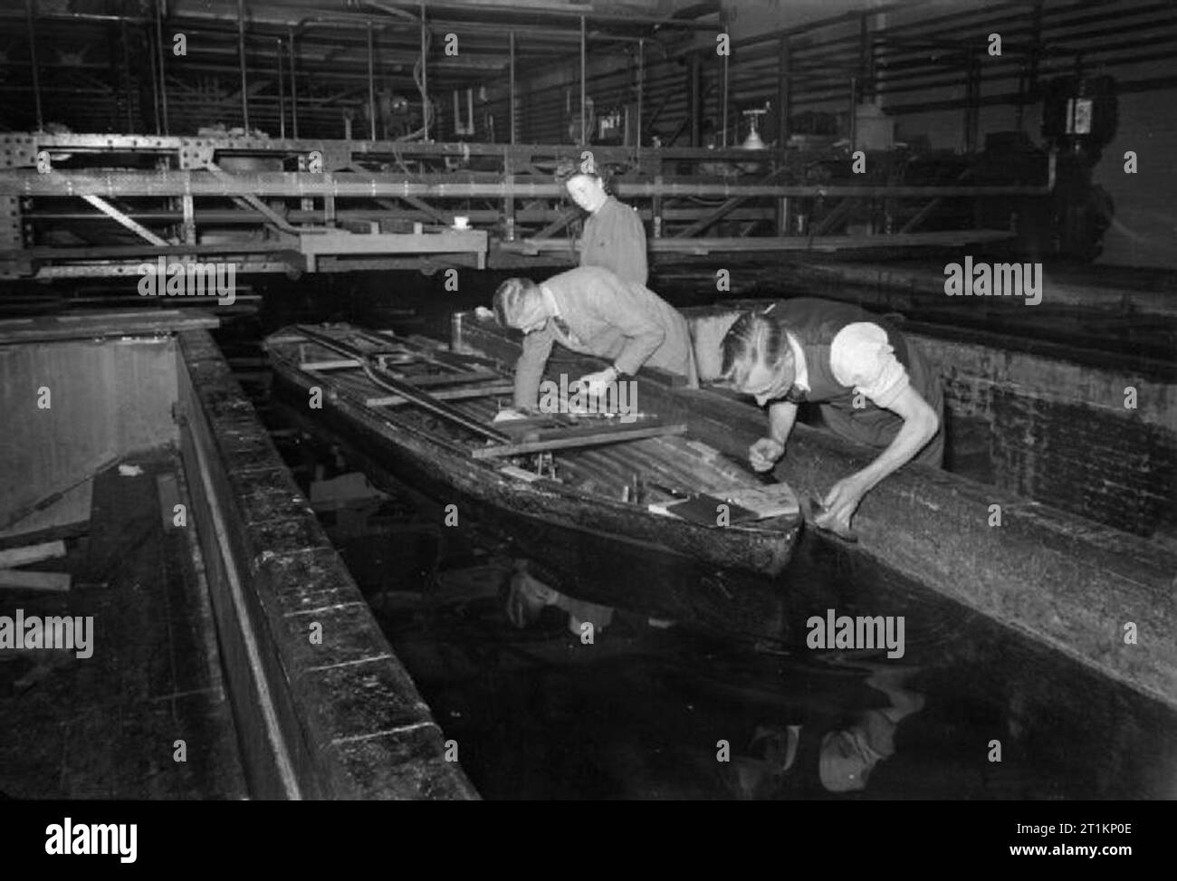 National Physical Laboratory- La science et la technologie en temps de guerre, Teddington, Middlesex, Angleterre, RU, 1944 Ministère de la recherche dans le navire au National Physical Laboratory, techniciens monter un petit moteur et l'engrenage de transmission d'un modèle réduit de navire qui est sur le point de subir un test d'auto-propulsion dans la cuve d'essai. Banque D'Images