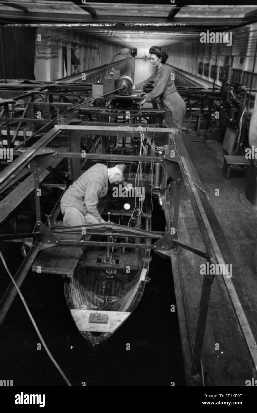 National Physical Laboratory- La science et la technologie en temps de guerre, Teddington, Middlesex, Angleterre, RU, 1944 Ministère de la recherche dans le navire au National Physical Laboratory, deux techniciens connectez l'appareil d'enregistrement d'un modèle de navire dans la cuve d'essai. L'appareil enregistrera tous les mouvements possibles du modèle dans différents tests, dont les résultats mèneront à des recommandations pour l'amélioration de l'efficacité de la conception. Banque D'Images