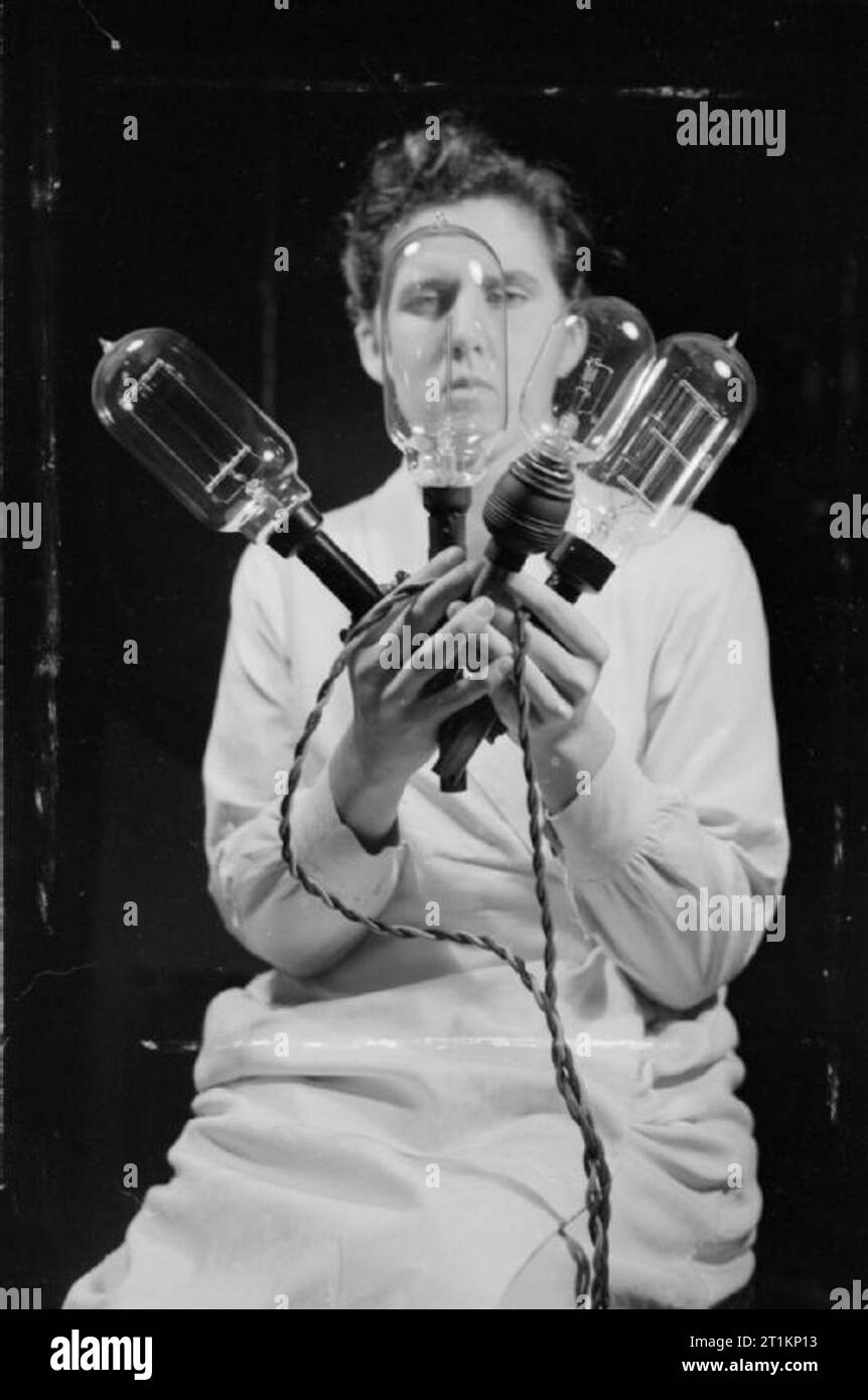 National Physical Laboratory- La science et la technologie en temps de guerre, Teddington, Middlesex, Angleterre, RU, 1944 dans la Section de photométrie de la Division légère au National Physical Laboratory, un technicien examine une sélection d'ampoules électriques qui sont utilisés comme des normes dans divers essais photométriques. Banque D'Images