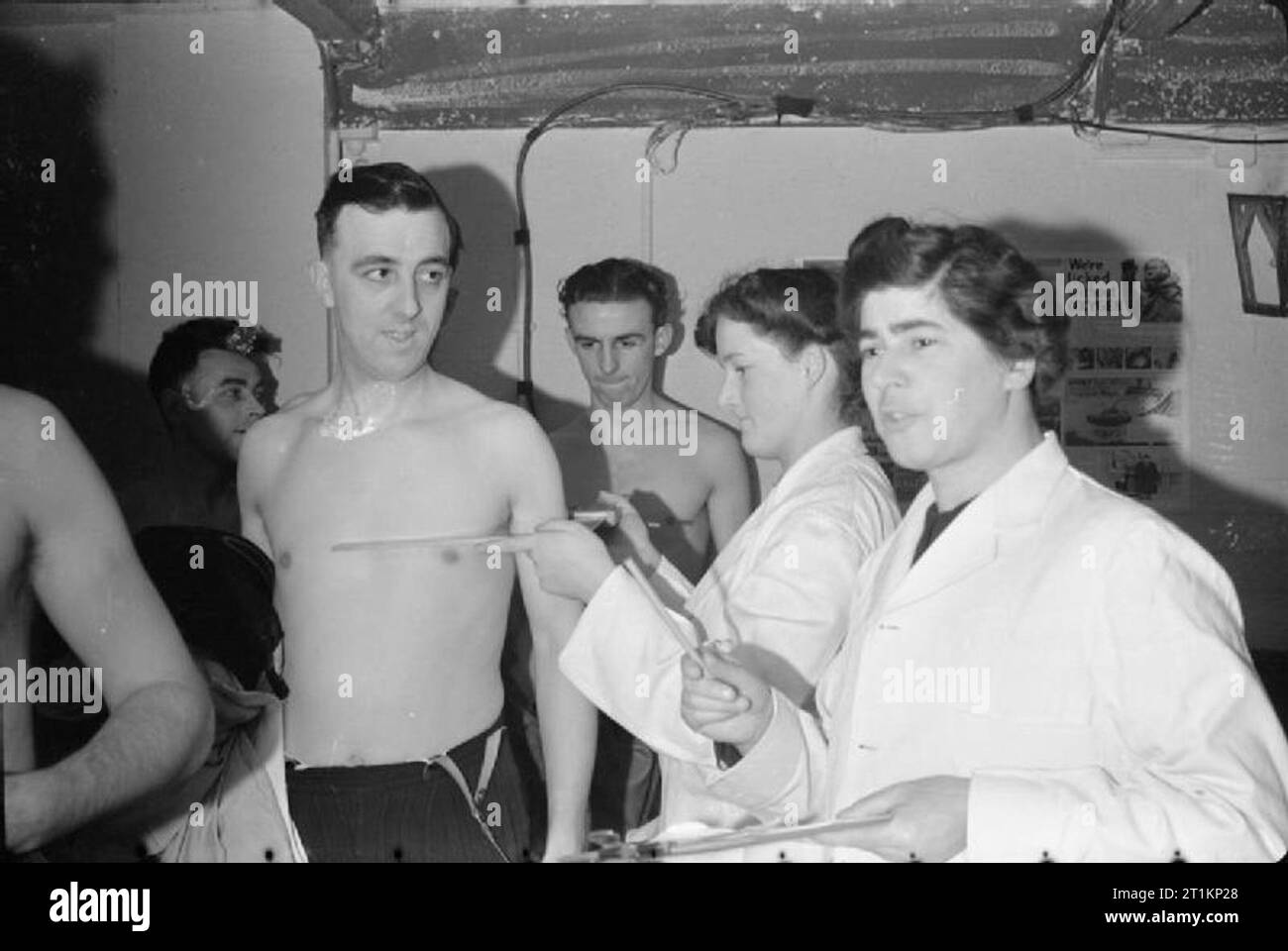 Nouvelle Guerre s'ouvre sur l'avant de l'usine- X-ray Le dépistage de la tuberculose, Londres, Angleterre, 1943, les ouvriers d'usine, maintenant dépouillés jusqu'à la taille, ont leur poitrine mesuré par les infirmières dans la clinique de fortune qui se tient à l'abri de l'usine de la cantine. Ces mesures de l'épaisseur de la poitrine fournira un guide pour l'exposition aux rayons x. Banque D'Images