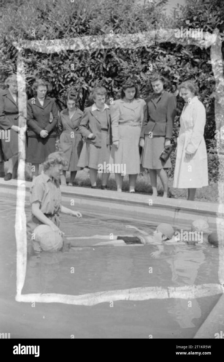 Lycéenne en infirmière- Formation médicale en Grande-Bretagne, 1942 étudiants sur un cours de formation en soins infirmiers, qu'ils prennent dans le cadre de leur dernière année à l'école primaire sont au bord d'une piscine extérieure et d'observer le traitement de la luxation congénitale de la hanche, qui est en cours dans l'eau. Une infirmière est dans l'eau avec un patient. Selon la légende originale 'radeaux flottants sont utilisés. La flottabilité de l'eau rend plus facile l'exercice musculaire". Banque D'Images