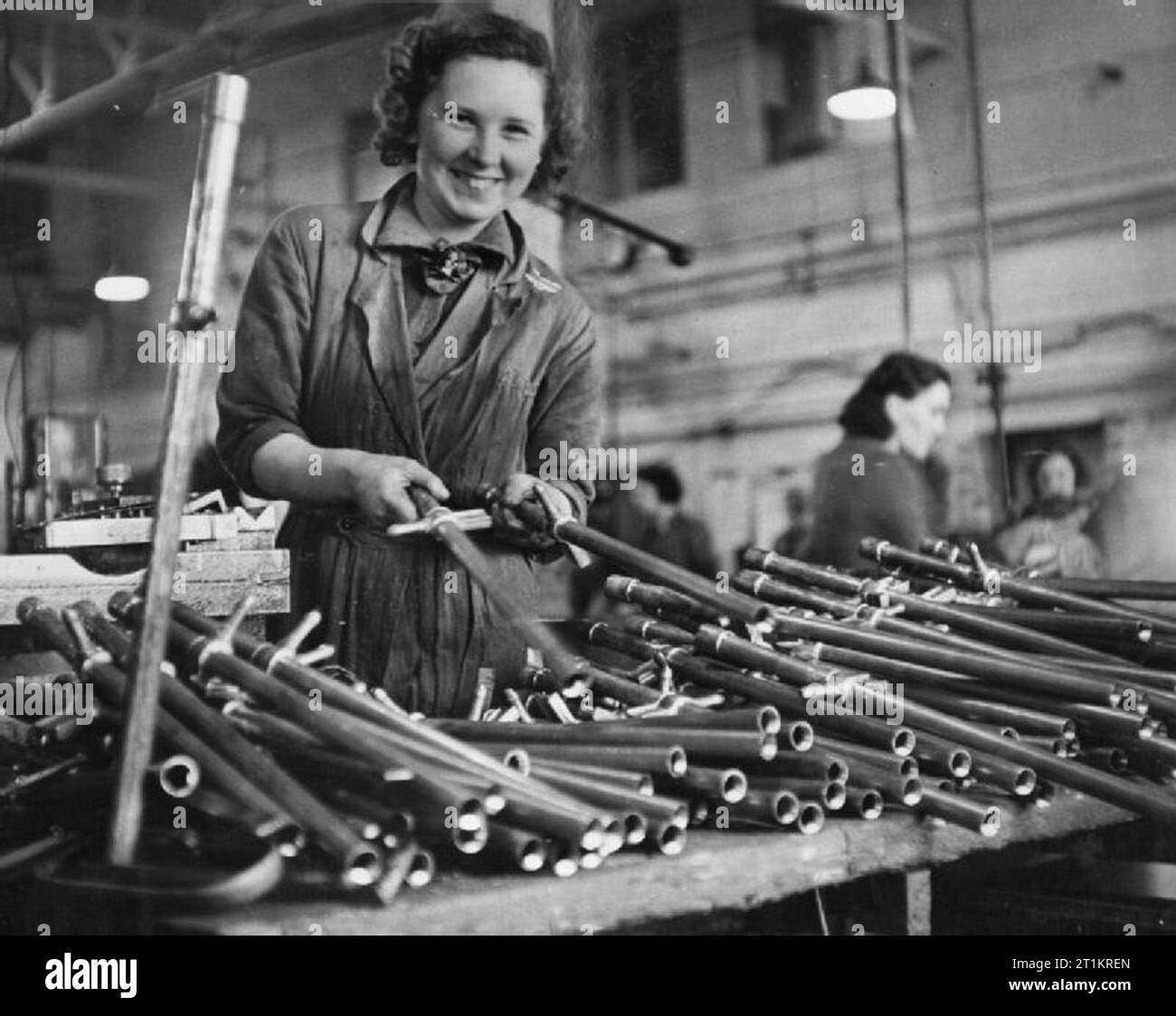La fabrication de la pompe de l'étrier, Angleterre, RU, 1941 Un tas de produits finis de la pompe de l'étrier de barils sont triés par une femme travailleuse de guerre à cette usine, la pompe de l'étrier quelque part en Grande-Bretagne. Banque D'Images