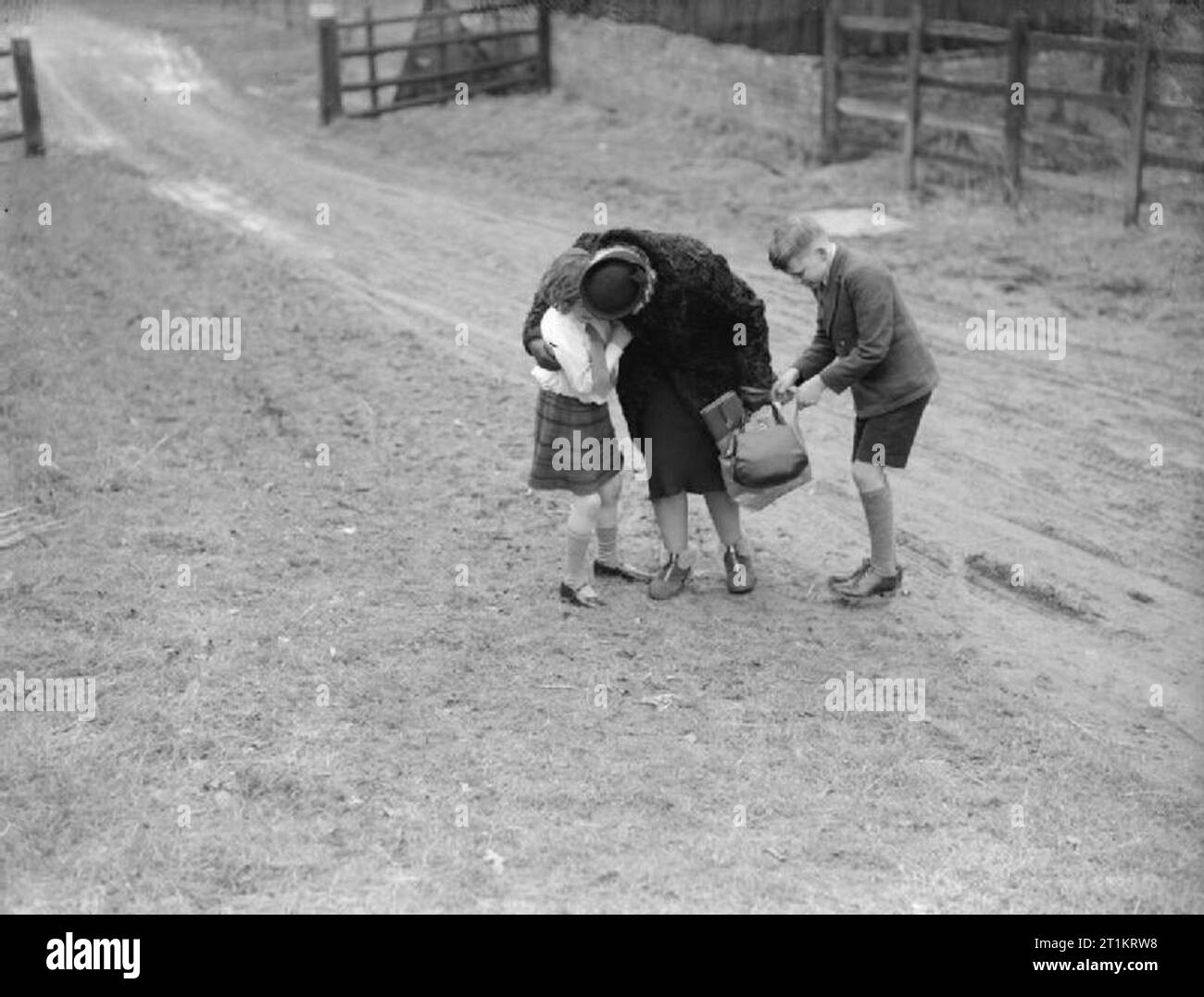 Les Carter en temps de guerre- la vie quotidienne d'une famille britannique sur le front intérieur, en Angleterre, C 1940 Mme Carter épouse sa fille Angela à son arrivée à la Hayward's Heath, dans le Sussex. Son fils Michael regarde dans son sac, pour voir si elle les a tous les cadeaux ! Michael et Angela ont été évacués à la Hayward's Heath et Mme Carter a voyagé de Londres Victoria à leur rendre visite. Banque D'Images