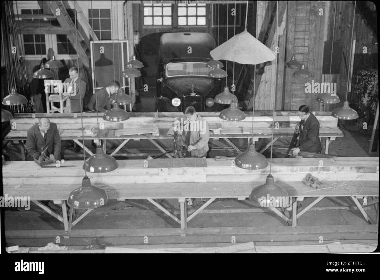 Ils combattent également qui seulement se tenir et attendre- industrie de guerre dans une ancienne maison de pays, 1942 l'homme au travail dans le garage attaché à M. et Mme Clark's country house, maintenant utilisé comme une petite usine de production de matériel de communication. Une voiture peut être vu dans l'arrière-plan. Banque D'Images