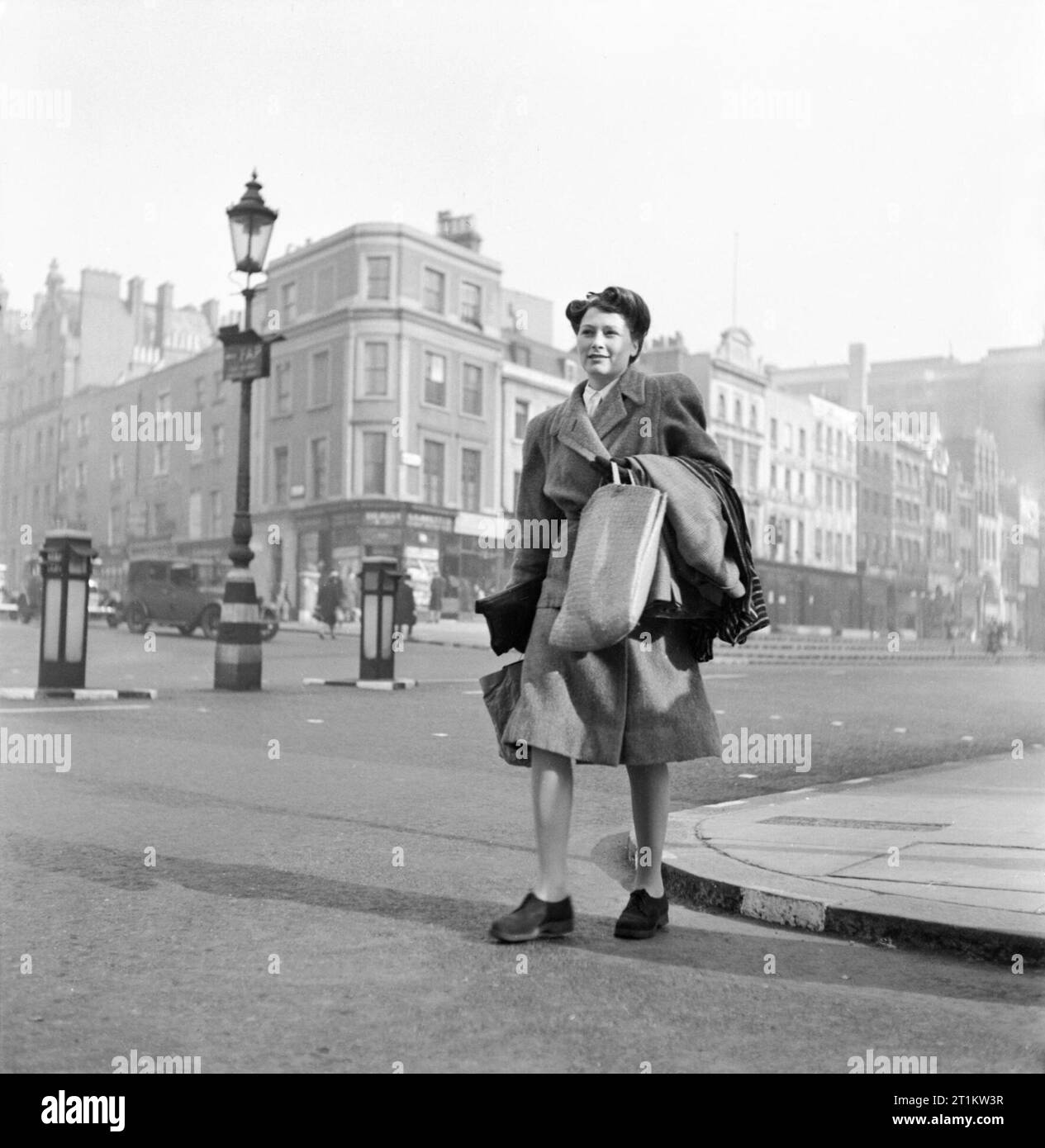 La vie de tous les jours- épouse de guerre en temps de guerre, Londres, mars 1943 Marcelle Lestrange porte ses achats à la maison après une journée de shopping. Comme il y a une pénurie de papier, aucun de ses achats ont été emballé : tous doivent aller dans son panier, ou comme les vêtements qu'elle a recueillies à partir de l'entretien, être drapé sur son bras. La légende originale précise également que : ' Shoppers prendre leurs propres journaux pour envelopper la viande ou du poisson, dans leurs propres sacs en papier de bonbons'. Banque D'Images