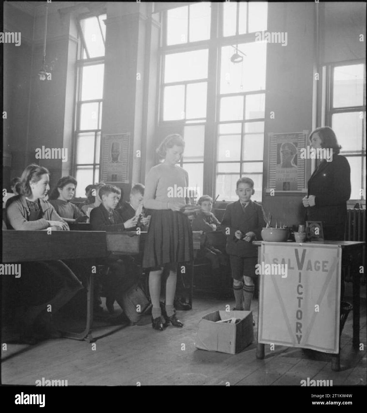 La guerre vient à l'école- La vie à Peckham Central School, Londres, Angleterre, 1943 Irene Parsons et Edward Perkins apporter leurs cartes de Noël à l'école pour la collecte de récupération, comme leurs camarades et l'enseignant. La boîte est sur le plancher à l'avant de la classe. Une table a une bannière avec les mots 'salvage' et 'victoire' se croisant à la 'V'. Des affiches autour de la chambre mettent en évidence l'importance de la contribution à l'effort de guerre des personnes dans les colonies. Selon la légende originale, père d'Irène est un tailleur et la maison familiale a été bombardée. Le père d'Edward est un boucher et il Banque D'Images