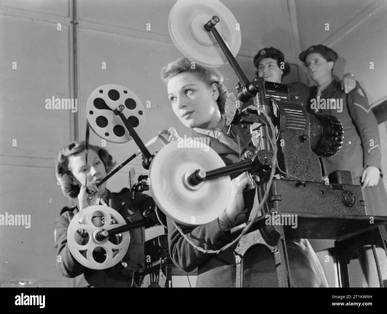 Projecteur Ciné ats Opérateurs, Aldershot, Hampshire, England, UK, 1941 Deux projectionnistes ciné de l'Auxiliary Territorial Service exploitation d'un 16mm De Vry Ampro Simplex projecteur à la rubrique stocke, Aldershot. Derrière eux, deux autres filles ATS stand dans le coin de la salle pour regarder la projection. Banque D'Images