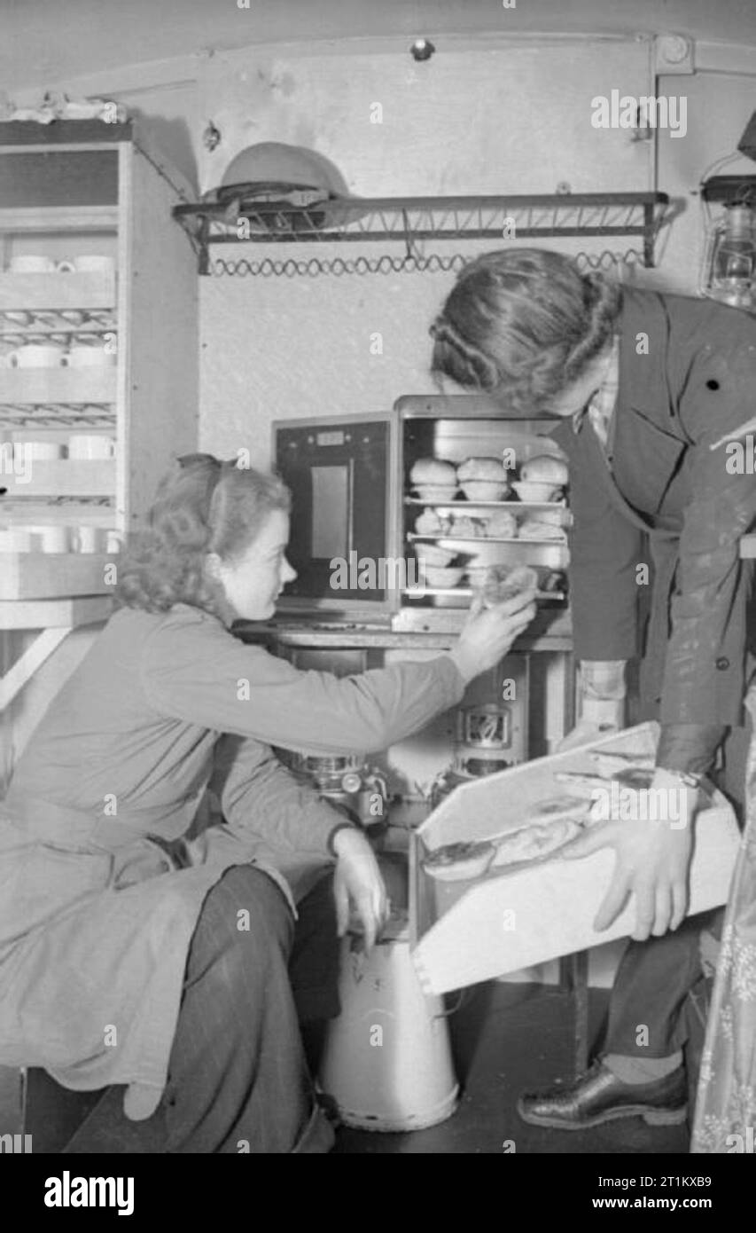 Cantine Blitz- les femmes du Women's Voluntary Service Exécuter une cantine mobile à Londres, Angleterre, 1941 Patience 'Boo' marque met en pâtés de viande à cuire dans le four au gaz dans la cantine mobile, de sorte qu'ils sont bien chaud lorsqu'il est servi pour hébergeurs, tandis que Rachel Bingham détient le bac. Ils sont tous deux membres de la WOMEN'S Voluntary Service et préparent la cantine avant leur départ de la WVS Canteen Service depot pour fournir des rafraîchissements pour les hébergeurs pour le travail après une nuit dans le refuge, Londres, 1941. Banque D'Images