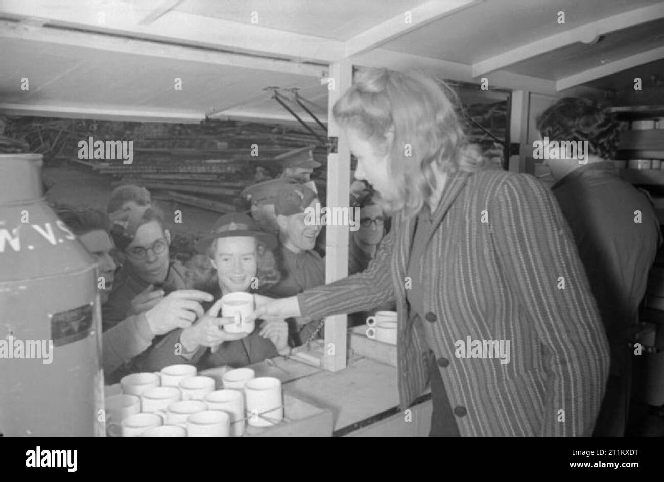 Cantine Blitz- les femmes du Women's Voluntary Service Exécuter une cantine mobile à Londres, Angleterre, 1941 Patience 'Boo' marque, un bénévole, WVS se dresse sur le "mauvais" côté du comptoir de la WVS canteen parmi un groupe de thirsty Pioneer Corps. Elle reçoit une tasse de thé d'un collègue à l'intérieur de la WVS cantine et est sur le point de le remettre à l'un des pionniers d'attente hommes Corps. Ces hommes ont aidé à effacer les décombres à la suite d'un raid aérien dans ce quartier de Londres, 1941. Banque D'Images
