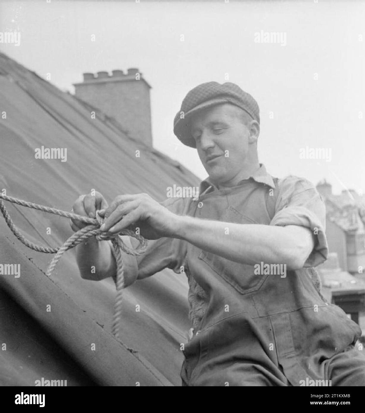 Blitz Repair Squad's Camp Londres- la vie quotidienne avec les équipes de réparation Blitz, Londres, Angleterre, RU, 1944 Naitby J Builder (à partir de la bâche à Darlington) liens familiaux le toit d'une maison endommagée par une bombe volante V1. Monsieur le Naitby fait partie de la 'Blitz' Repair Squad, une équipe de constructeurs qui sont venus à Londres, provenant de diverses régions du pays pour réparer ces dommages. Selon la légende originale, M. Naitby est également membre de la police spéciale du comté de Durham. Banque D'Images