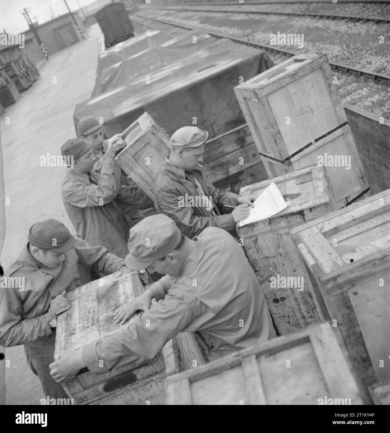 Produits britanniques en gares de triage- anglo-américain la coopération en temps de guerre La Grande-Bretagne, 1943 soldats américains déplacer des grands distributeurs de pièces de rechange de moteur de voiture à côté de la ligne de chemin de fer à ce triage, quelque part en Grande-Bretagne. Le sergent Charlie Oliver, du Walton Way Extension, Augustin, Géorgie (centre) vérifie les boîtes dans. Banque D'Images