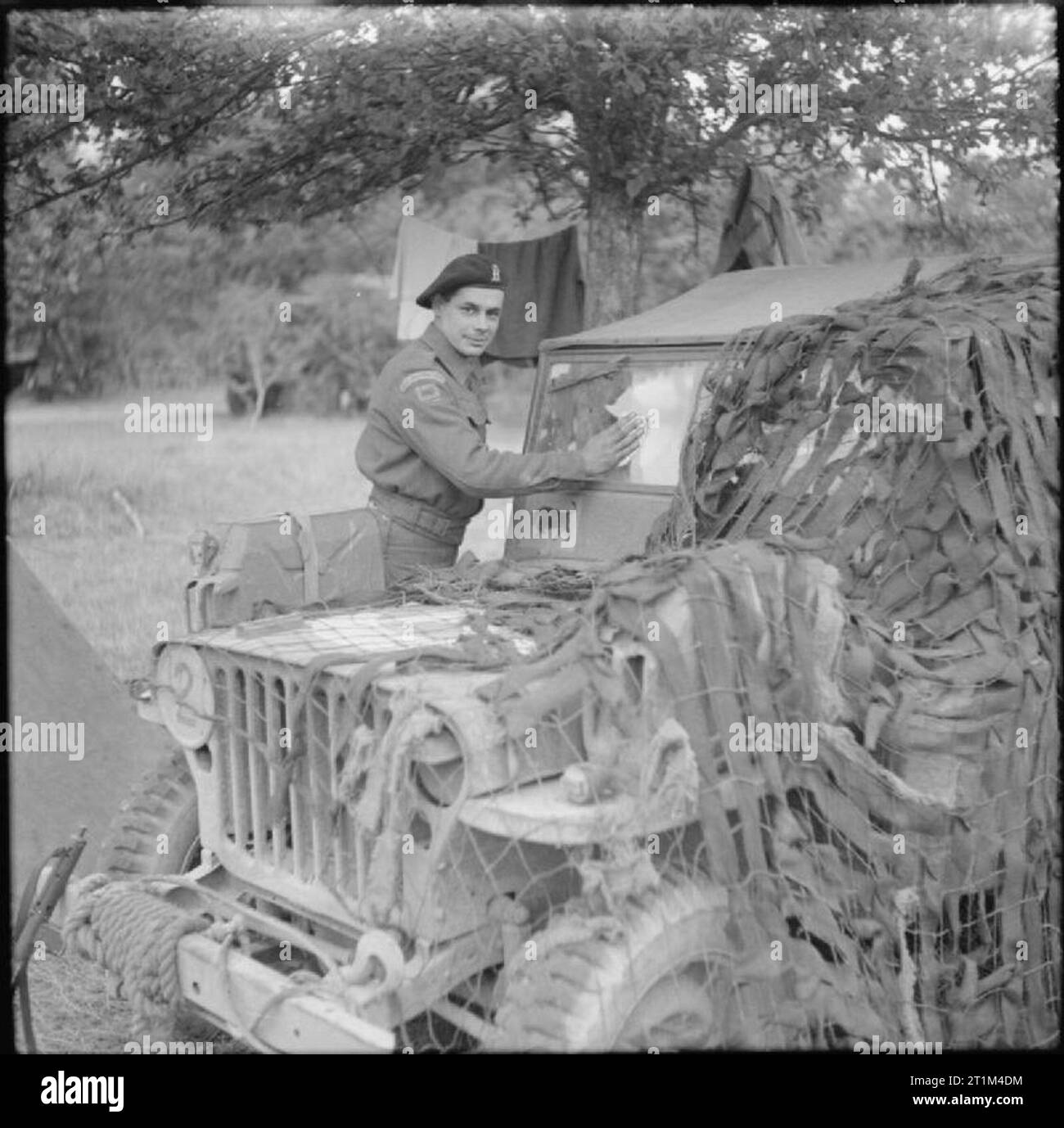 L'Armée britannique en Normandie, juillet 1944 Trooper M Fraser, du Corps Blindé Royal, 11e Division blindée, le nettoyage du pare-brise d'une Jeep Willys MB. Remarque le 'red-horned bull' Insigne de la 11e Division blindée sous le pare-brise. Banque D'Images