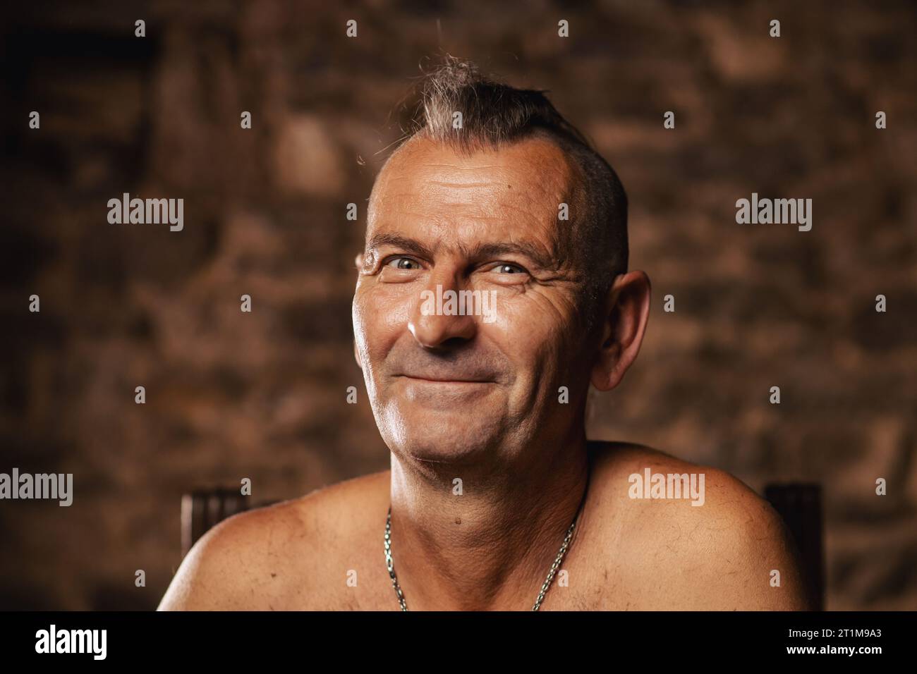 Un homme plus âgé satisfait, âgé de soixante ans, sourit et regarde la caméra. Banque D'Images