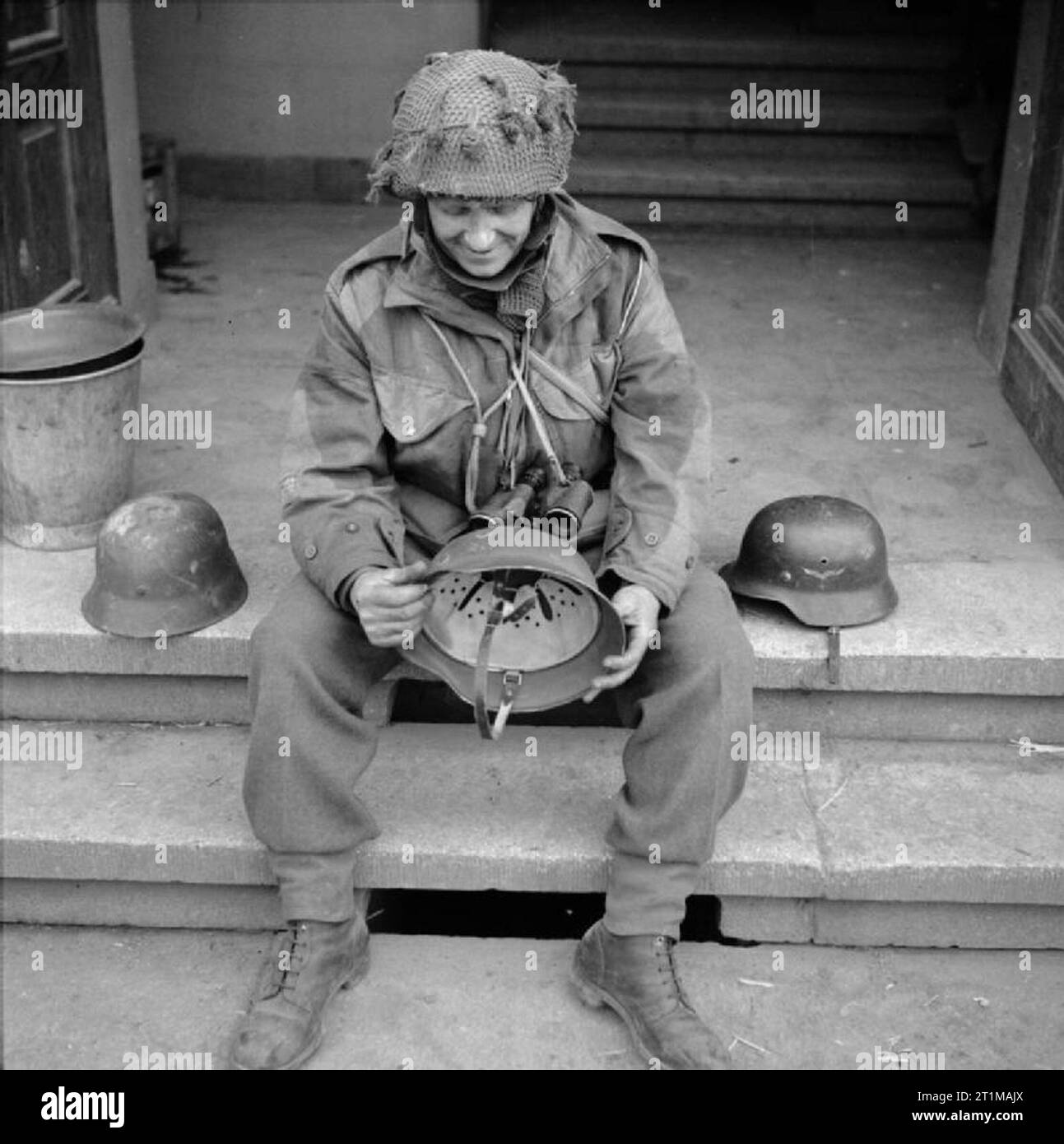 L'armée britannique dans le Nord-Ouest de l'Europe 1944-45 RSM Allen du 12th Devonshire Regiment examine les casques allemands capturés à Hamminkeln, le 25 mars 1945. Banque D'Images