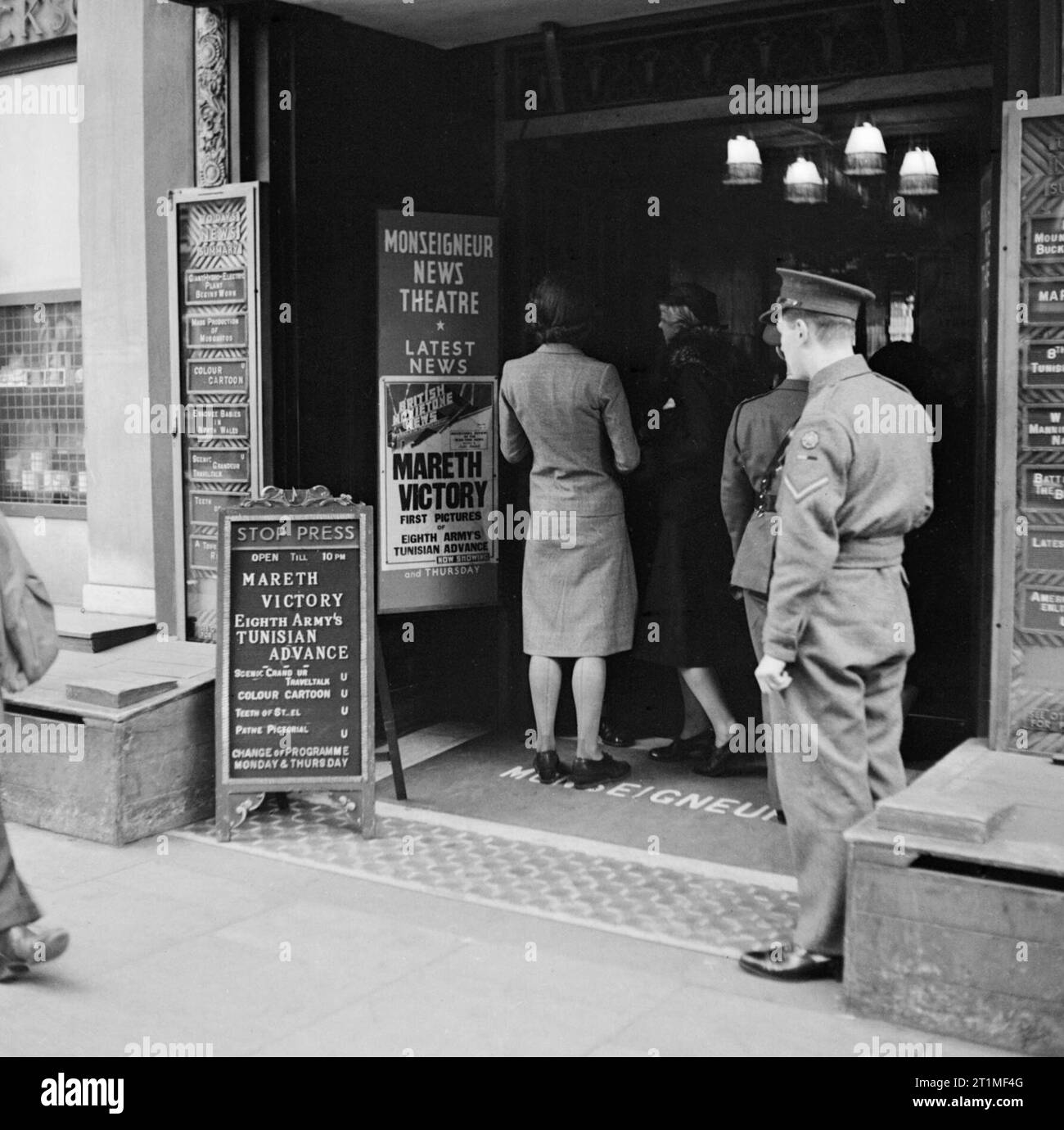 Le front intérieur en Grande-Bretagne durant la Seconde Guerre mondiale, des cinémas et de cinéma : dans le hall de l'Monseigneur News Theatre de Leicester Square, Londres, caporal suppléant se penche sur la publicité pour British Movietone News coverage du 'Mareth victoire'. Banque D'Images