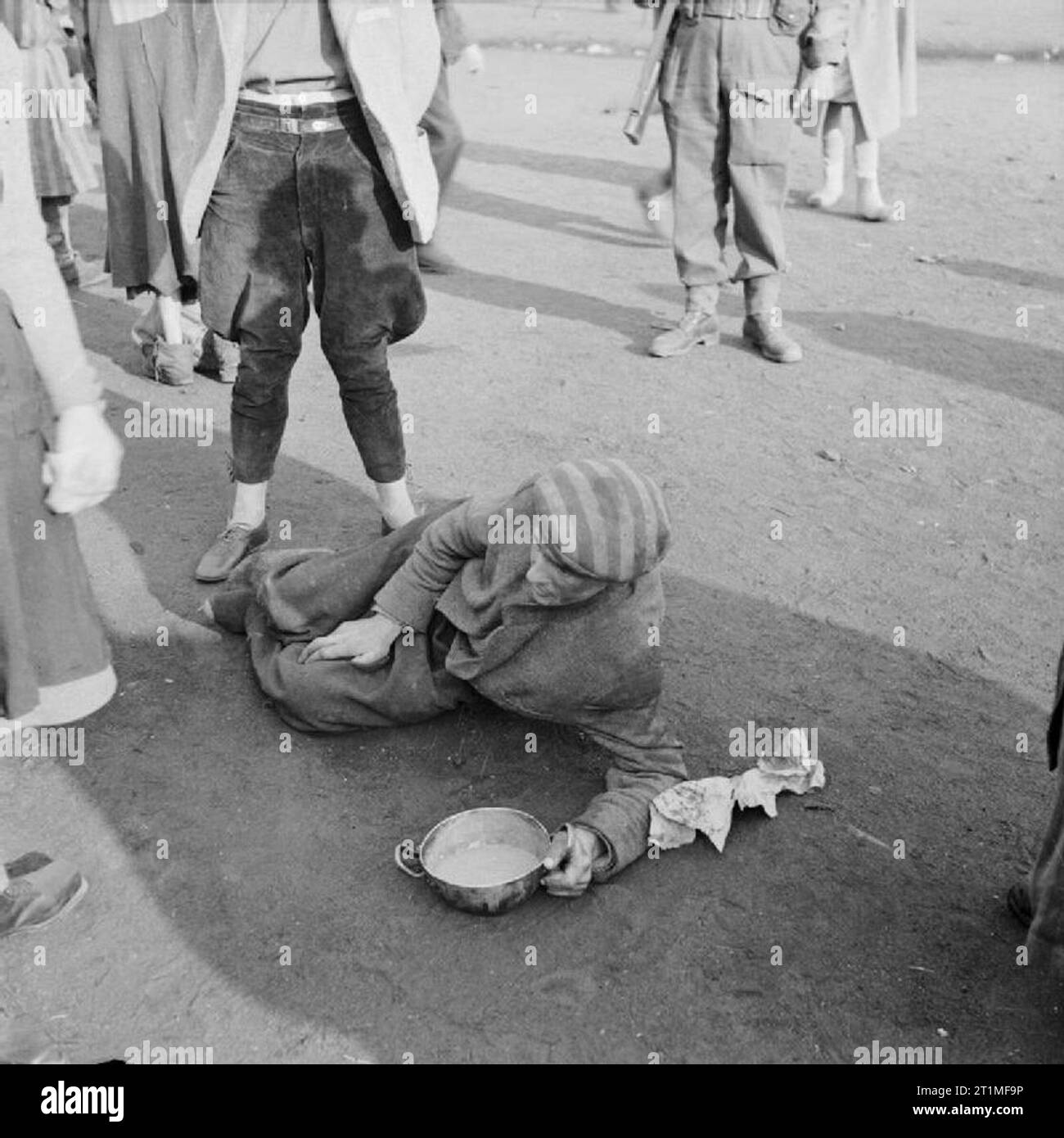 La libération du camp de concentration de Belsen Bergen-avril 1945, un détenu, trop faibles pour se tenir debout, se débat pour boire une soupe amené par l'un des détenus du camp des femmes. Banque D'Images