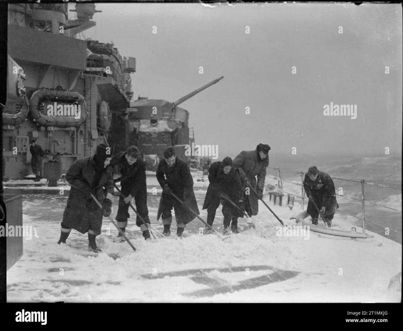 La Royal Navy pendant la Seconde Guerre mondiale, les marins à démêler l'écheveau de la neige à bord du HMS KING GEORGE V tandis qu'elle était dans les eaux de l'Arctique. Les ponts ont été souvent un pied dans la neige profonde. L'une de ses tourelles de 5,25 pouces peut être vu dans l'arrière-plan. Banque D'Images
