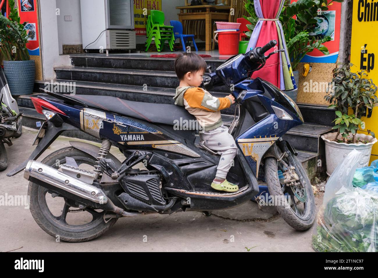 Cat Ba, Vietnam. Jeune garçon explorant la moto. Banque D'Images