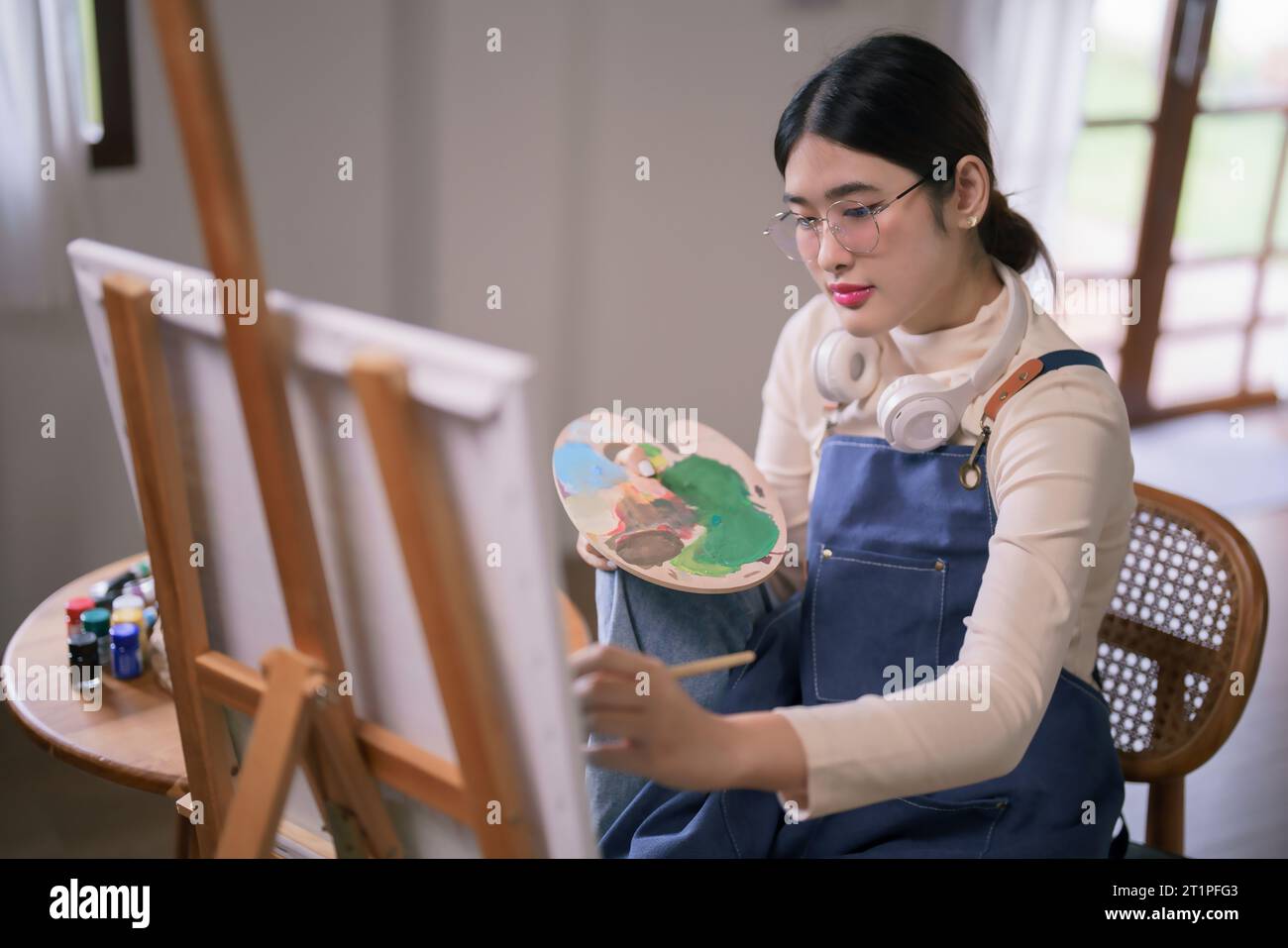 Jeune artiste féminine asiatique utiliser le pinceau et la couleur pour dessiner et peindre créer des œuvres d'art sur toile. Banque D'Images