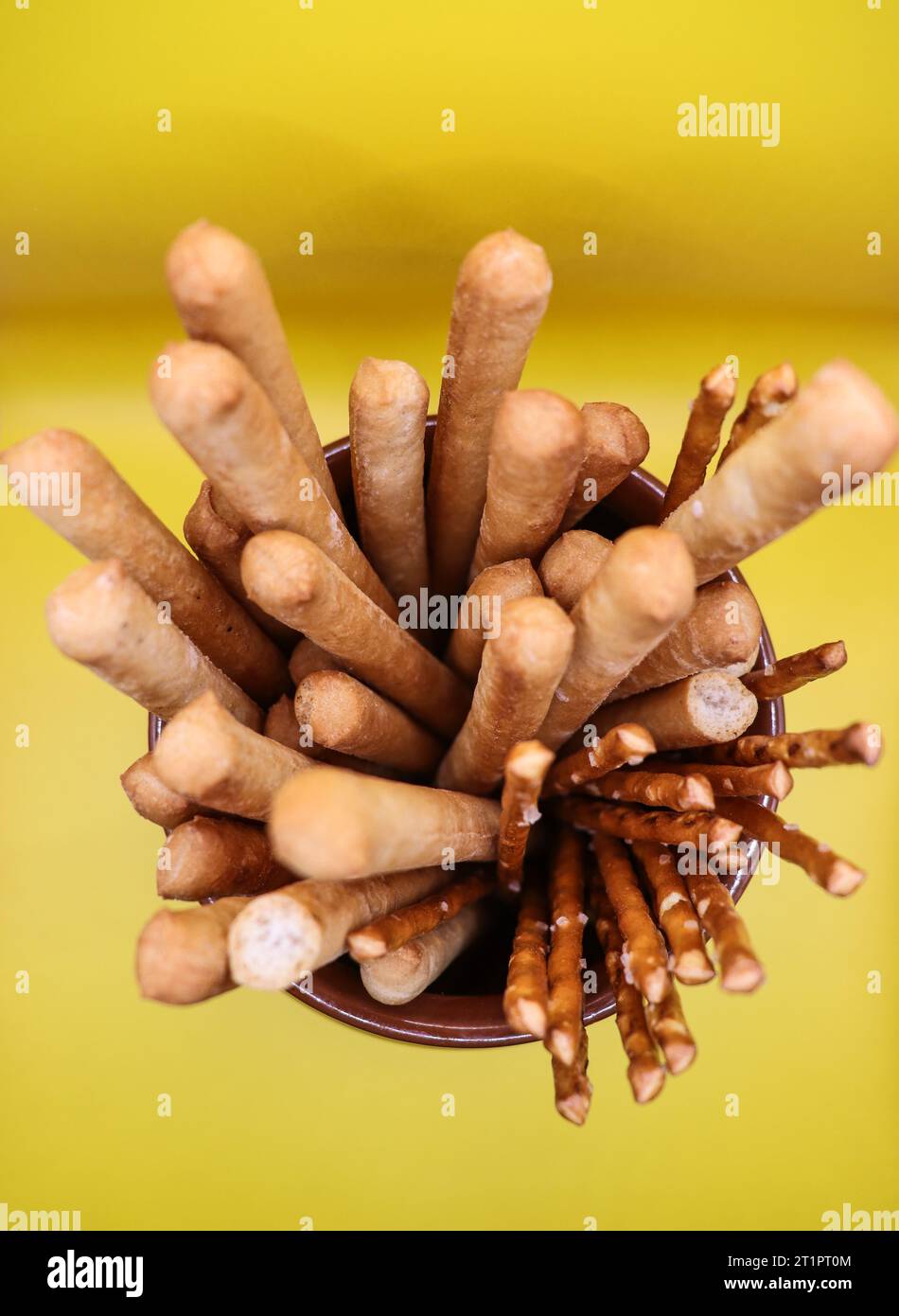 Un bouquet de collations croquantes dans un bol en céramique sur un fond jaune Banque D'Images