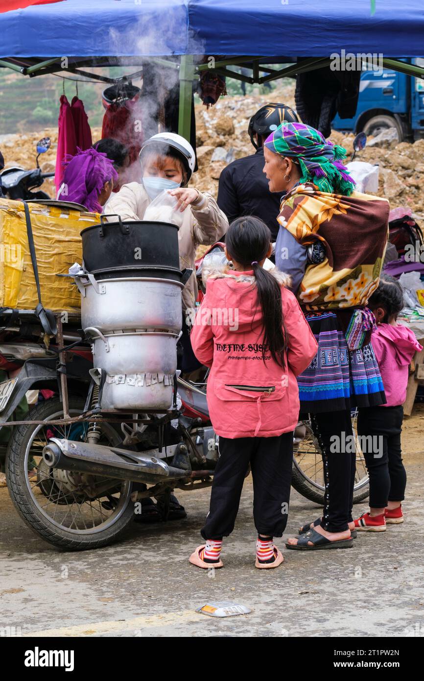 Scène du marché de CAN Cau, Vietnam. Mère et enfants Hmong achetant de la nourriture du fournisseur. Province de Lao Cai. Banque D'Images