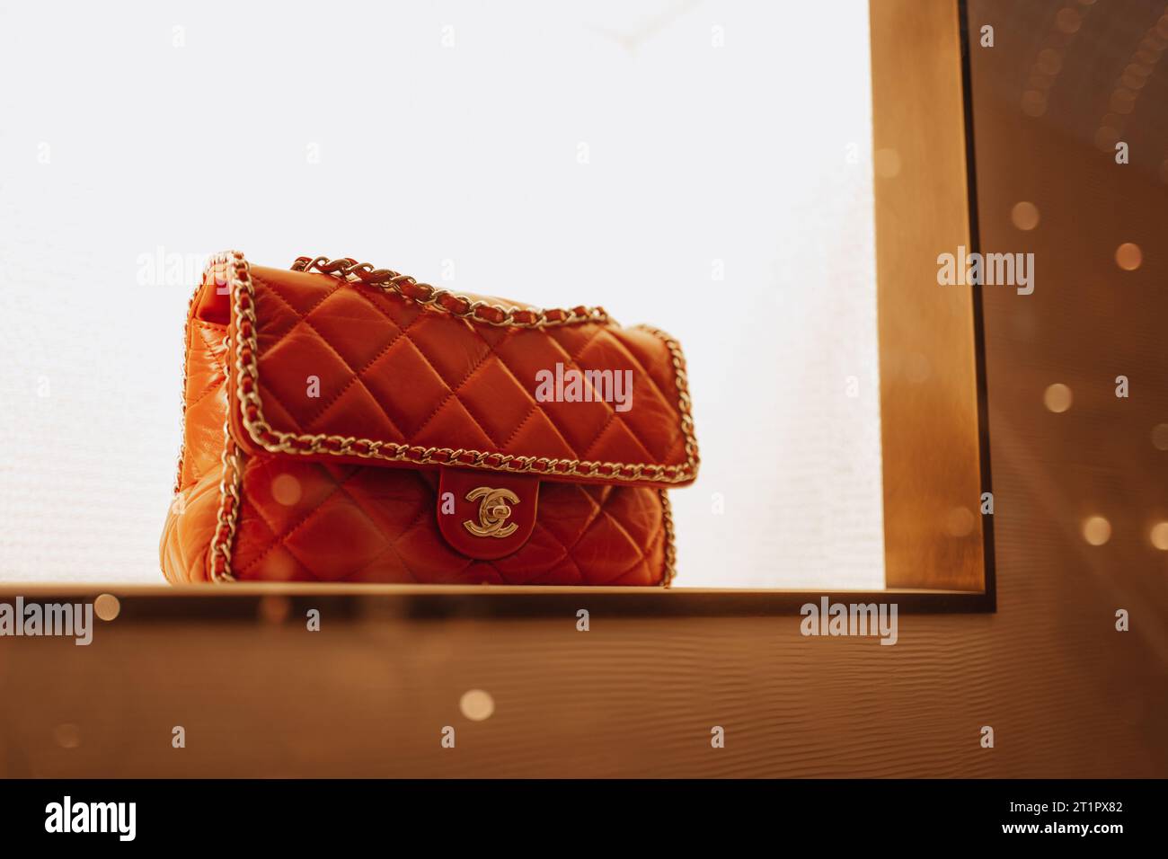 Sac à main Chanel féminin rouge orange chic avec chaîne dorée dans la fenêtre d'un magasin de luxe. Chanel est une marque de haute couture fondée par Coco Chanel en 19 Banque D'Images