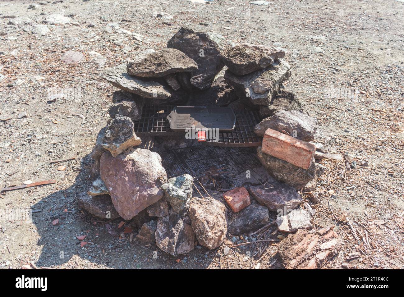 Un barbecue pique-nique fait de briques posées sur le sol et une poêle à frire grillée en fer. Banque D'Images