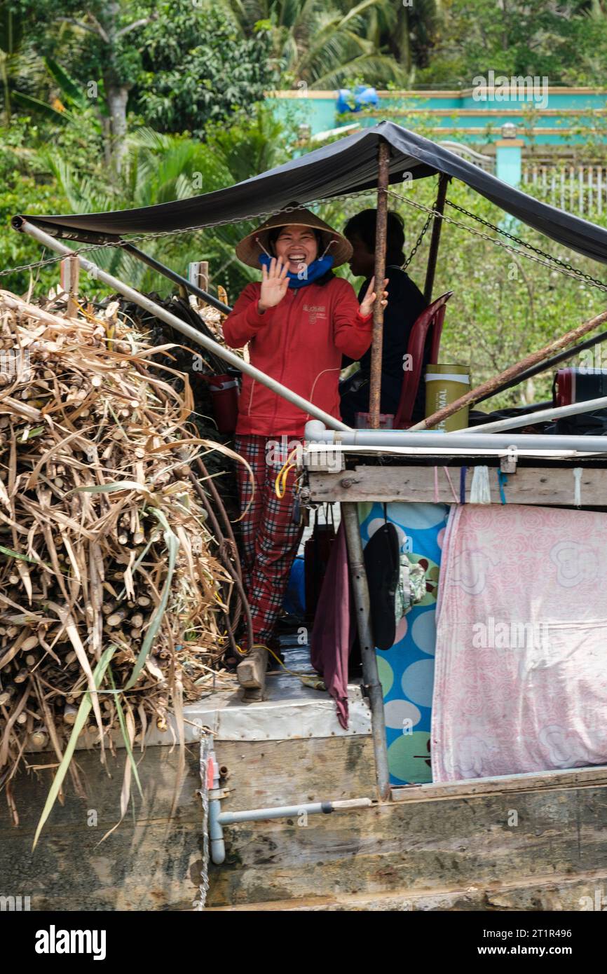 Femme sur un petit bateau transportant de la canne à sucre sur le Mékong, Vietnam. Banque D'Images