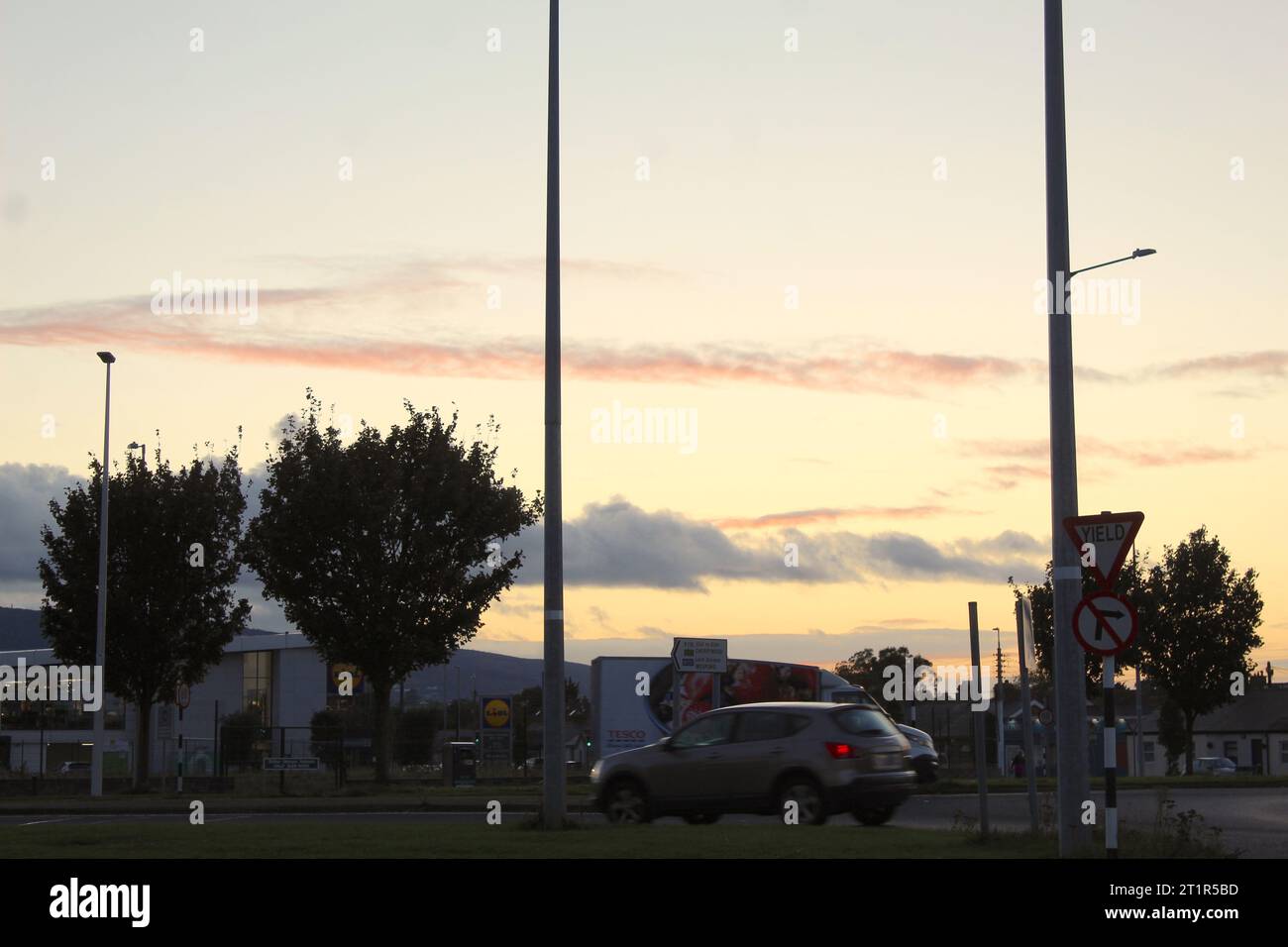 Une photo d'un centre commercial, de voitures et d'un centre commercial pendant la soirée. Banque D'Images