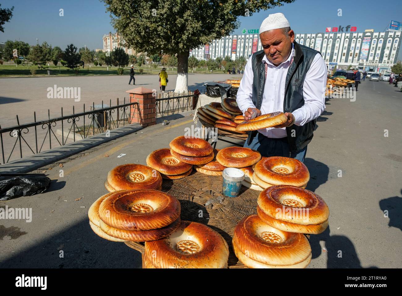 Namangan, Ouzbékistan - 15 octobre 2023 : un homme vendant du pain devant la madrasa mollah kirghize à Namangan, Ouzbékistan. Banque D'Images