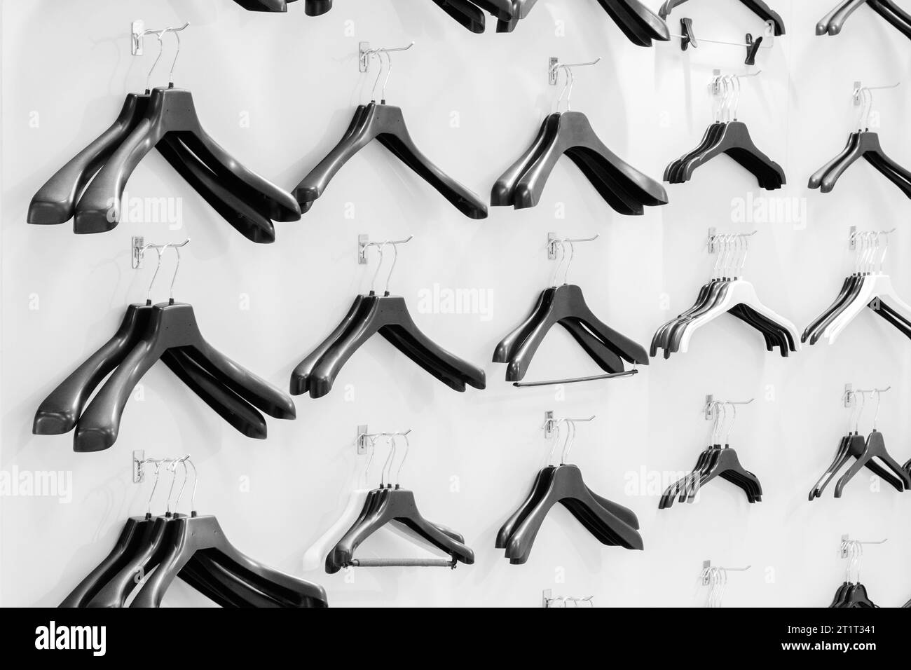 Cintres en plastique vides noirs assis sur un mur blanc dans un magasin, concept de vente Banque D'Images