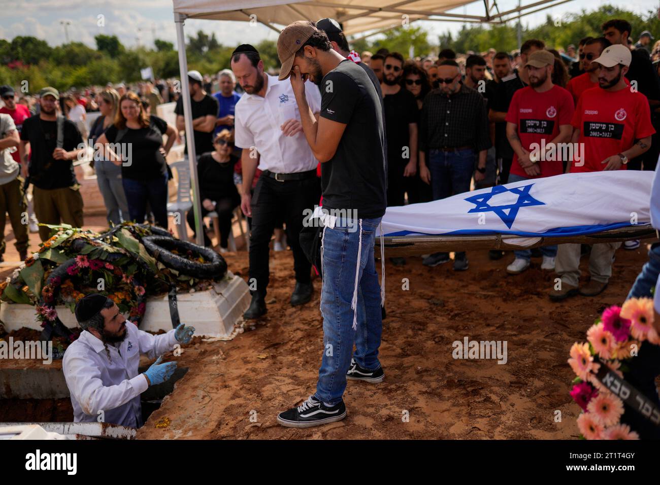 Covered with the Israeli flag, the body of Ben Fishman is buried at Pardes Haim cemetery in Kfar Saba, near Tel Aviv, Israel, Sunday, Oct. 15, 2023. Fishman was killed when Hamas unleashed its attack on thousands of Jews attending a music festival in southern Israel earlier this month. (AP Photo/Francisco Seco) Banque D'Images